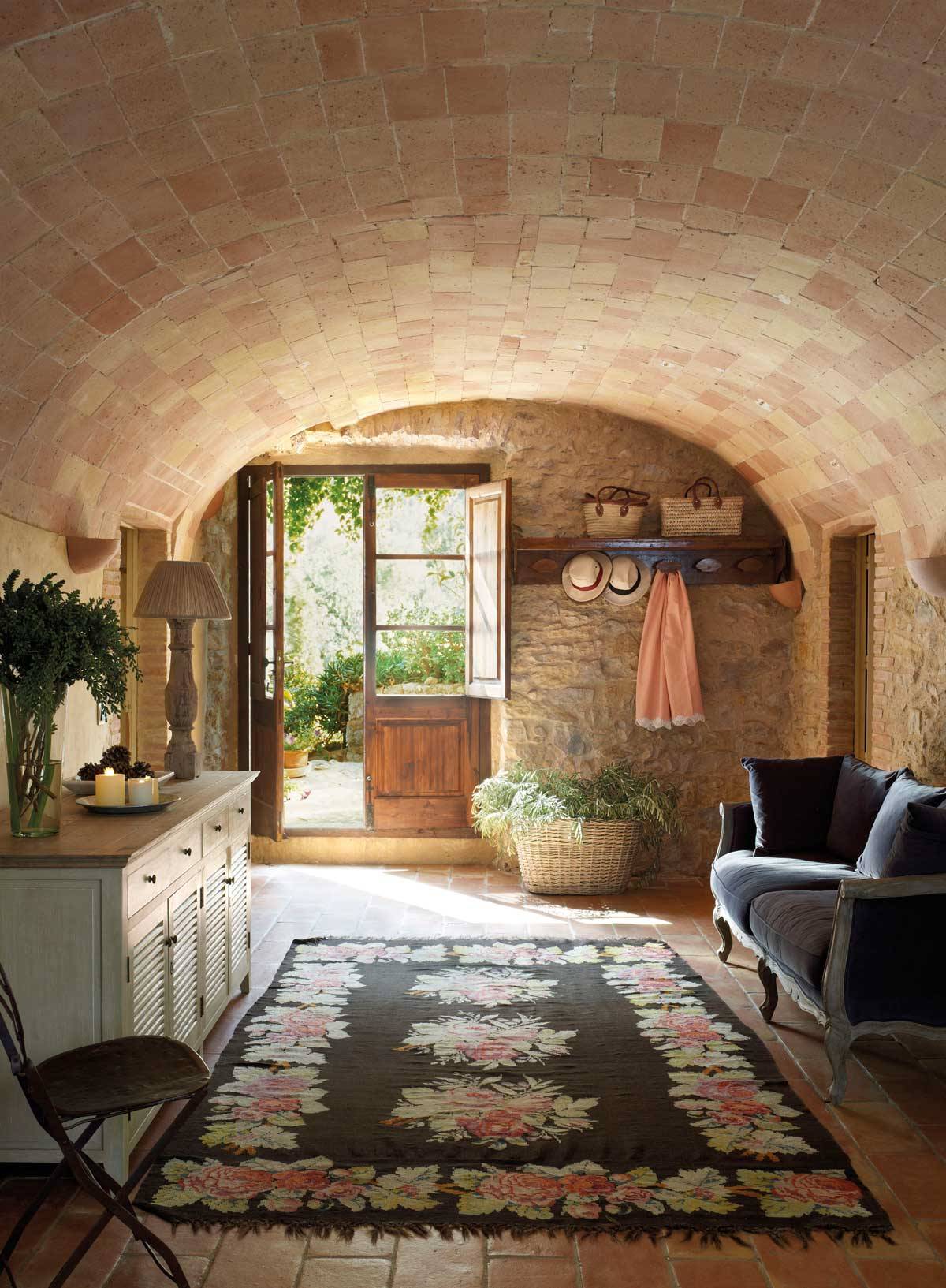 Recibidor rústico con techo abovedado, pared de piedra, suelo de toba y alfombra-308014