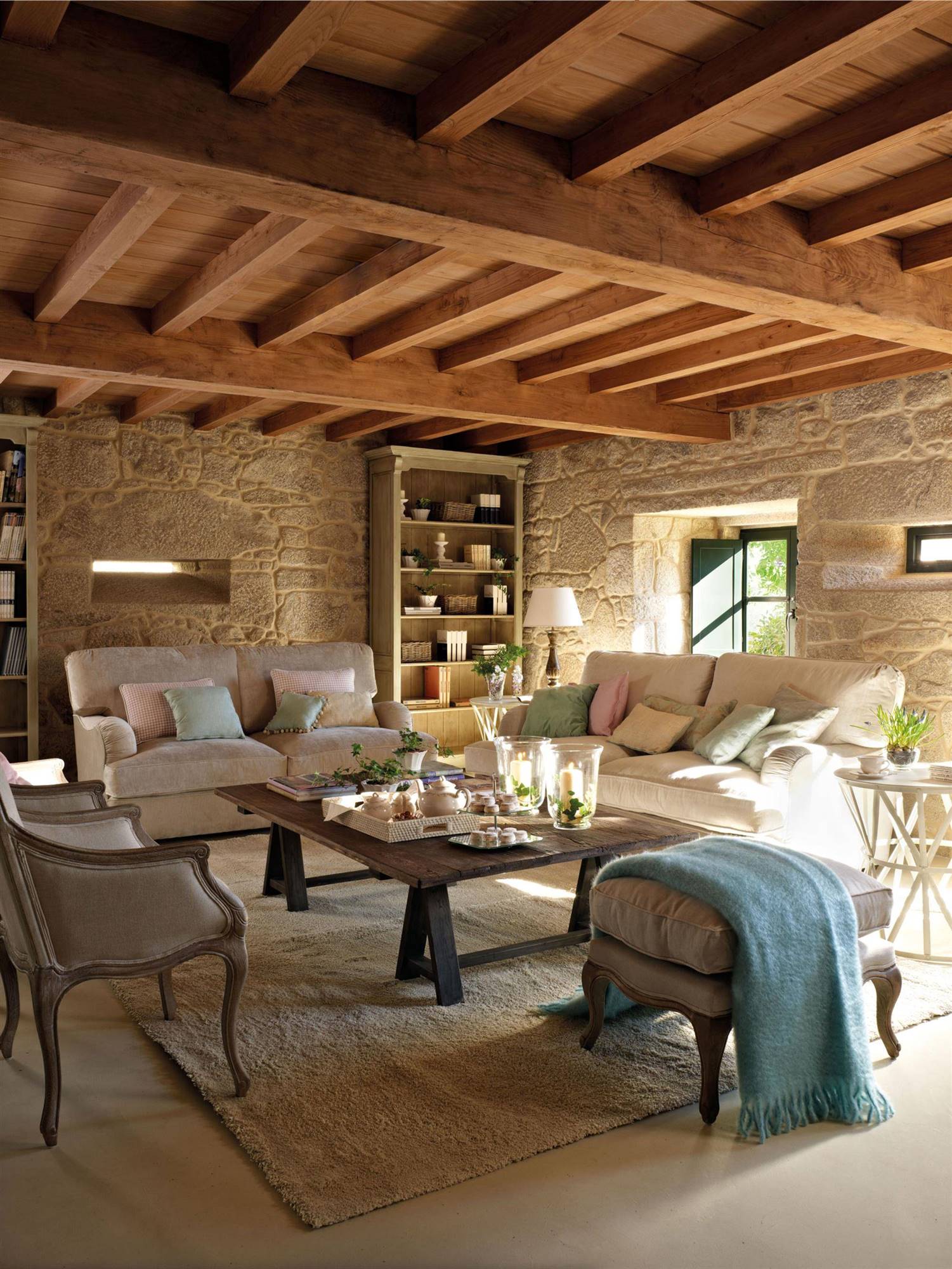 Salón rústico con paredes de piedra y sofás beige. 