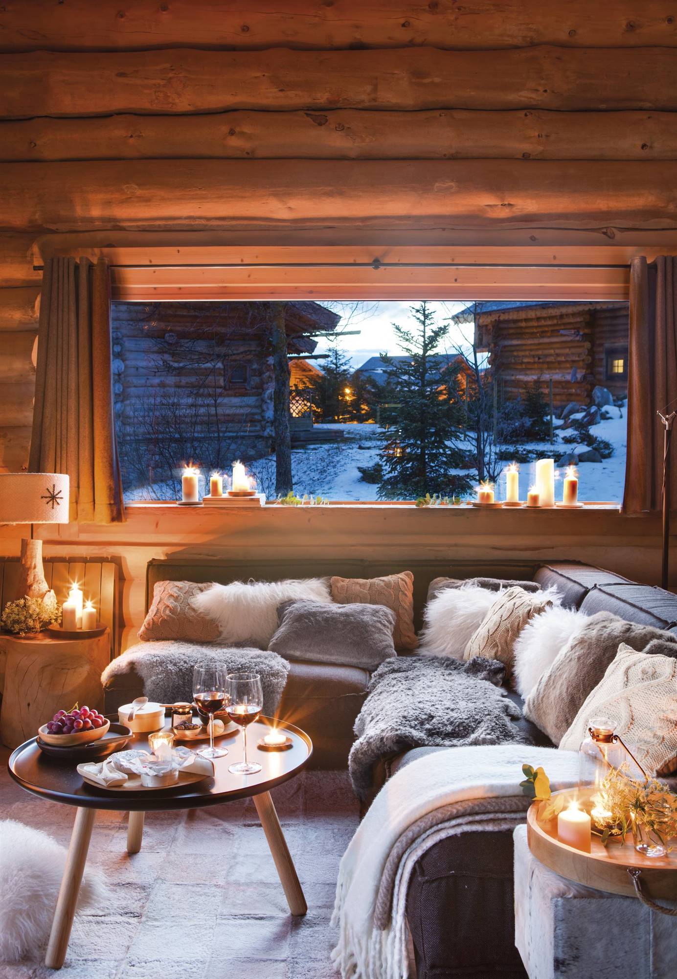 Salón rústico con paredes de madera y ventana con paisaje nevado.
