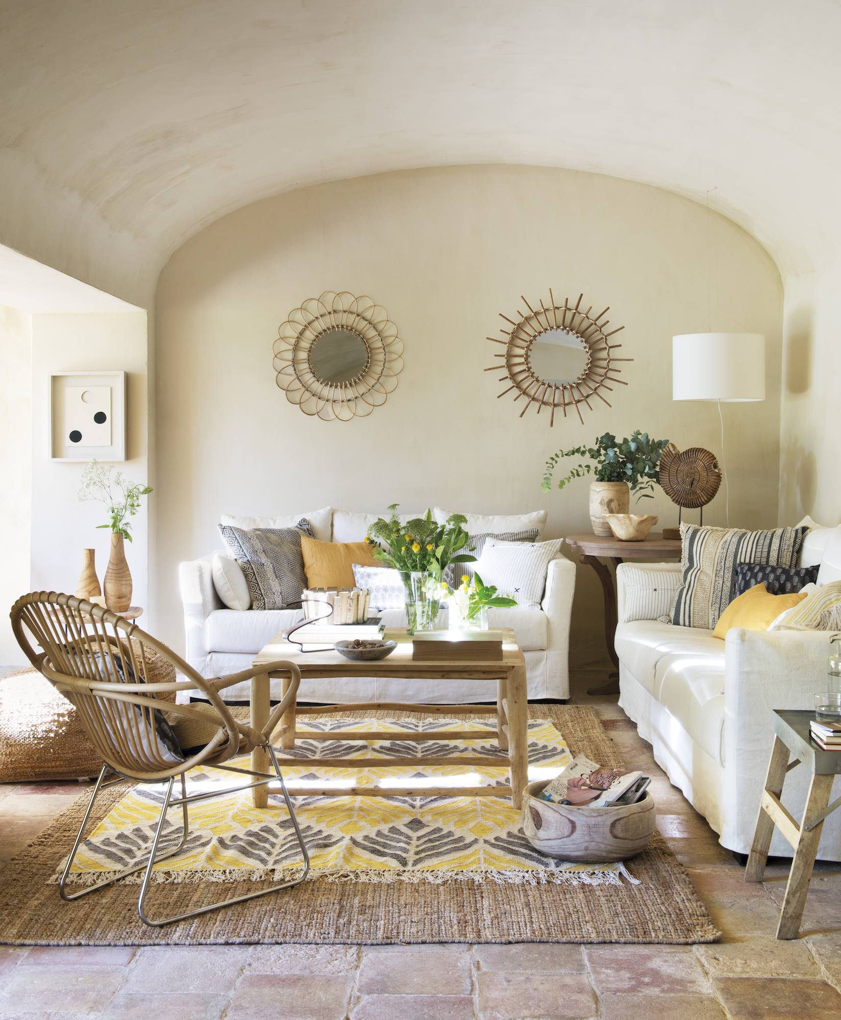 Salón rústico en beige con sofás blancos y techo abovedado. 
