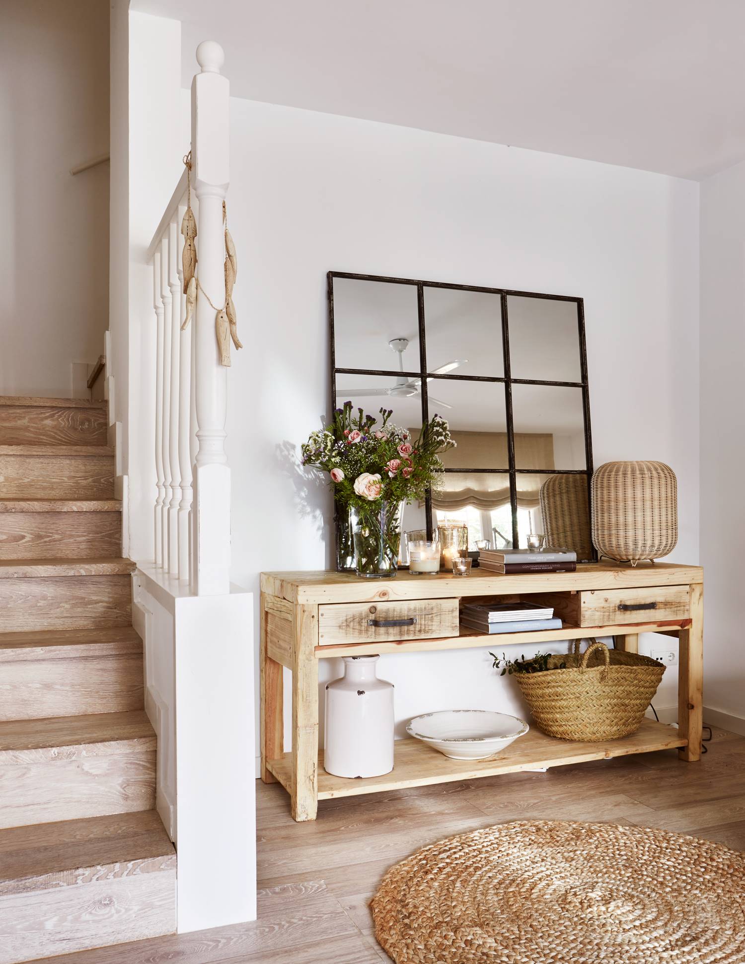 Un recibidor rústico con paredes blancas, mueble de madera y espejo de cuarterones.