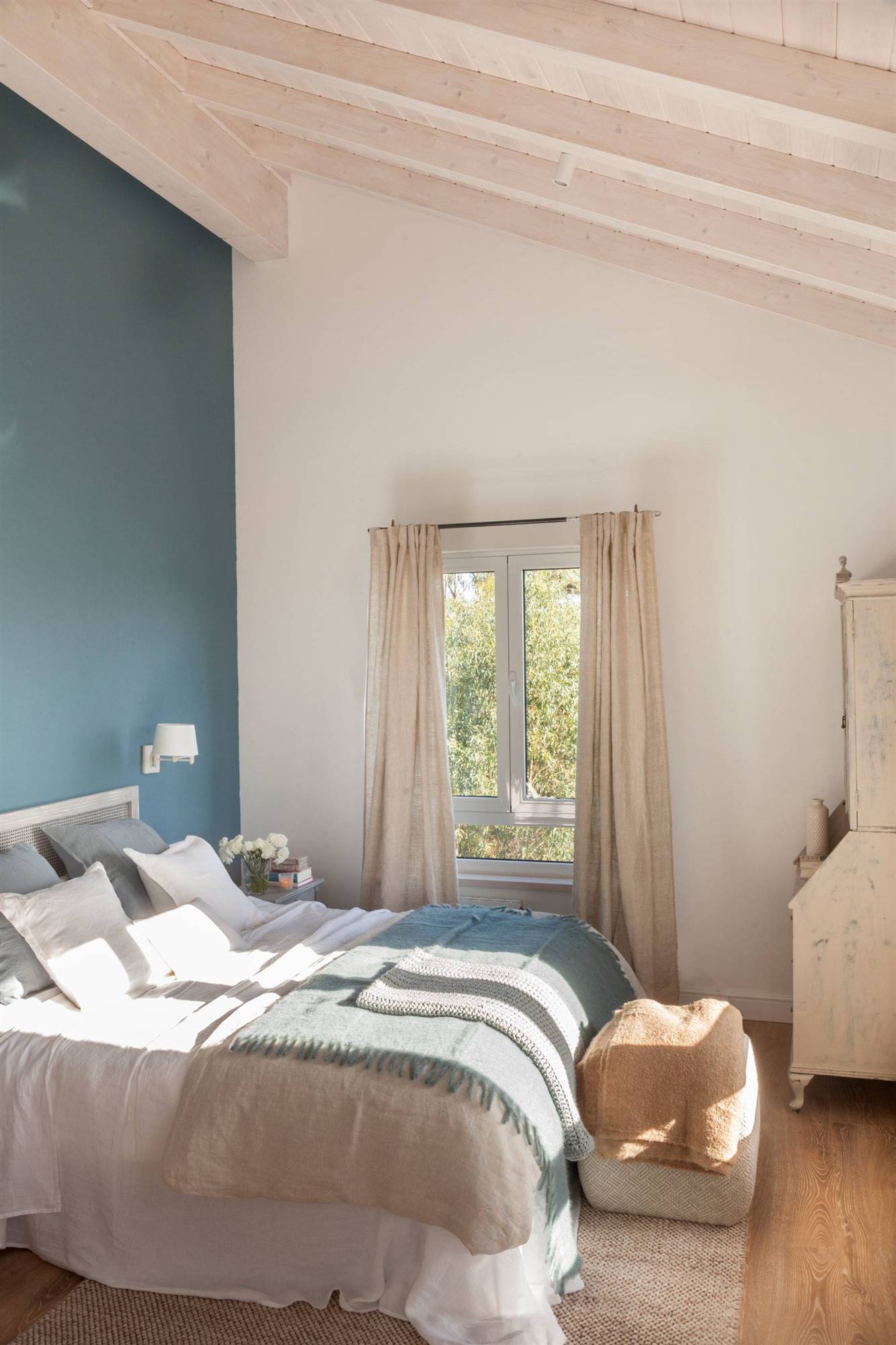 Dormitorio con la pared del cabecero pintada en azul. 