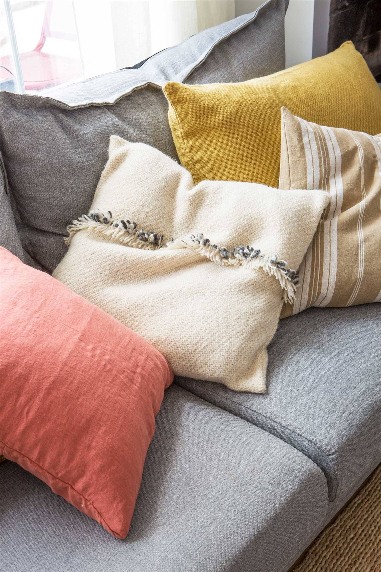 Sofá gris con cojines de lino y lana. 