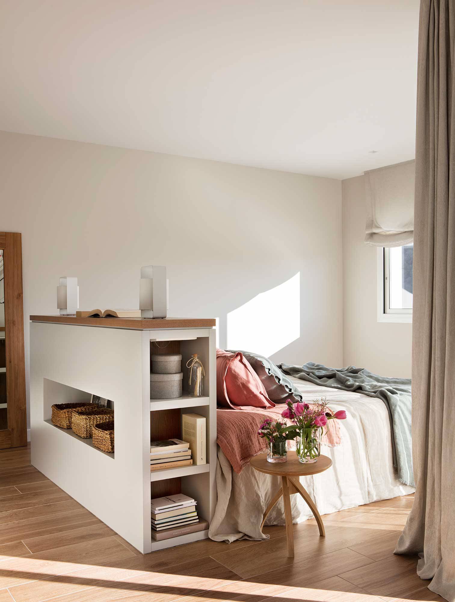 Dormitorio con cama en medio y cabecero murete con hornacian y estantes