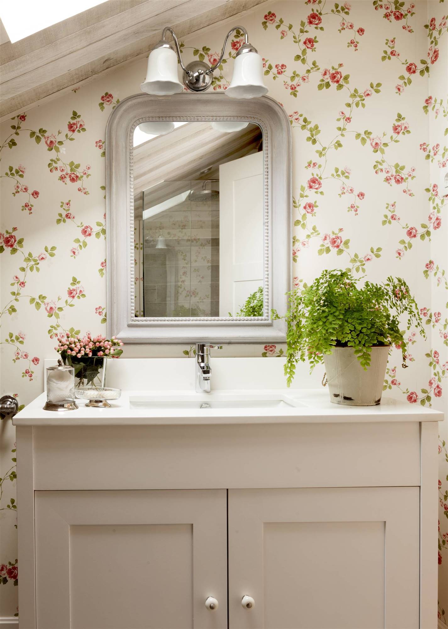 Baño abuhardillado y papel pintado floral. 