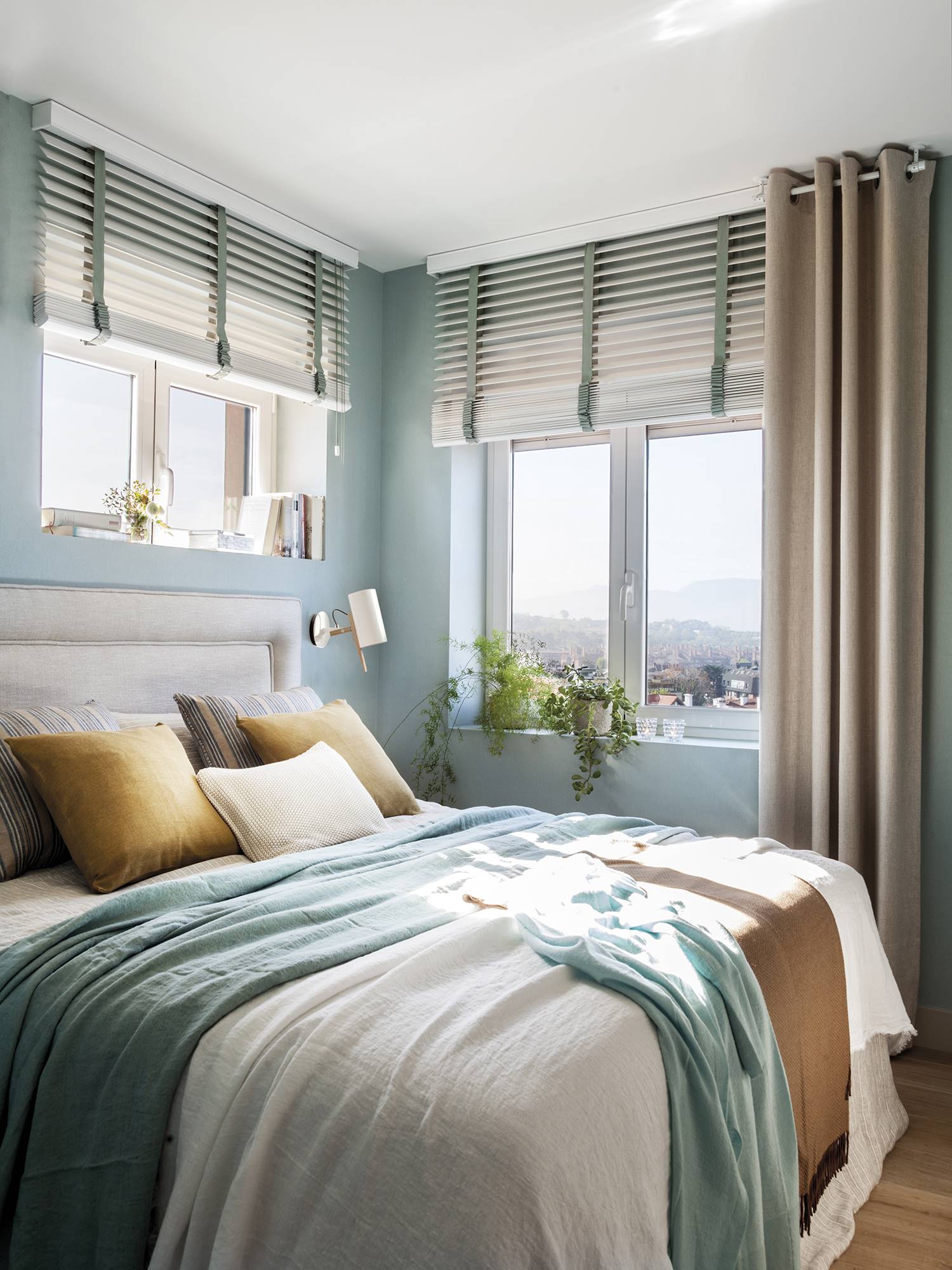 Dormitorio en color azul verdeagua con cabecero tapizado en blanco. 