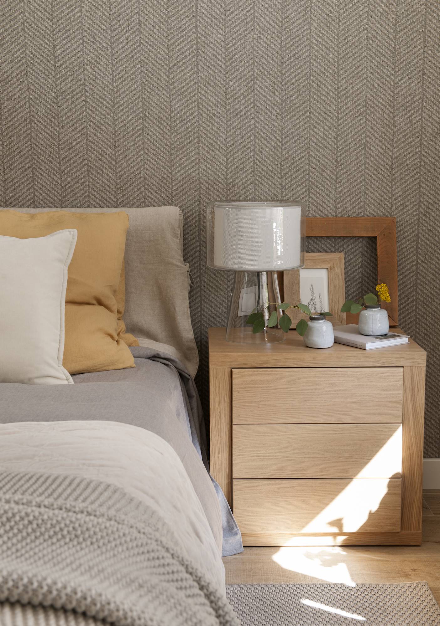 Dormitorio con la pared del cabecero tapizada con papel espiga en color beige.