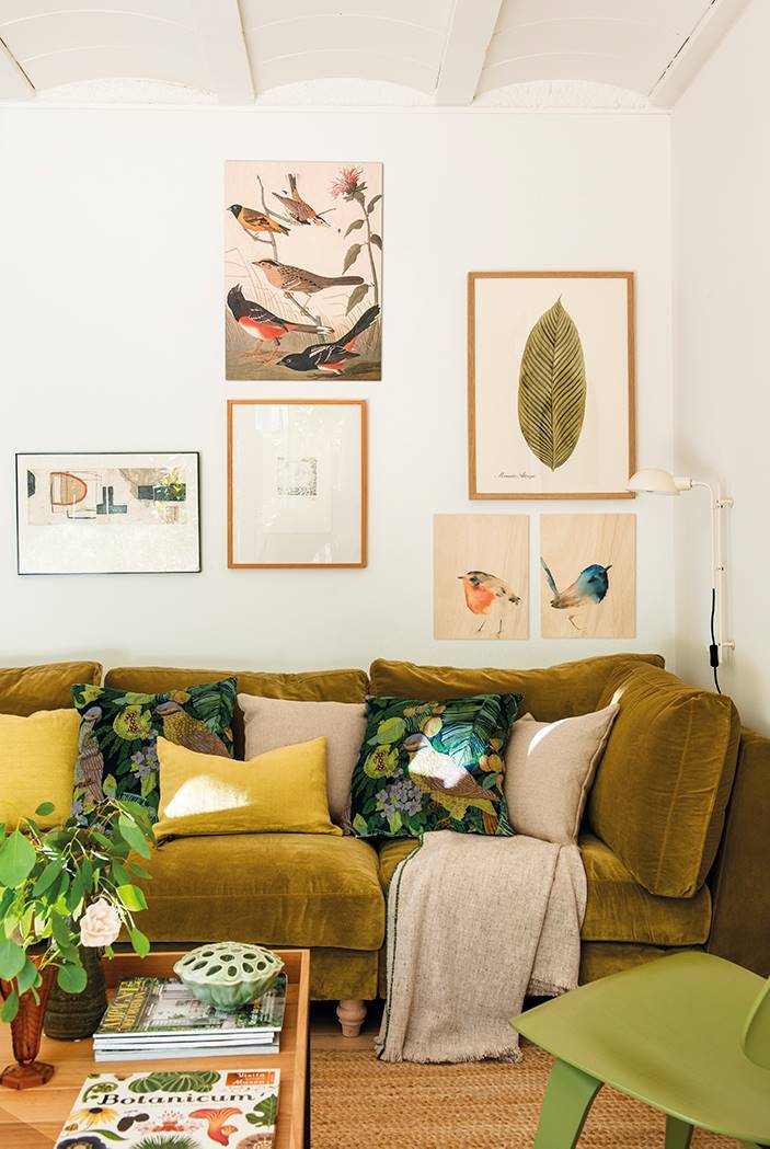 Salón con sofá de terciopelo verde y cojines botánicos. 