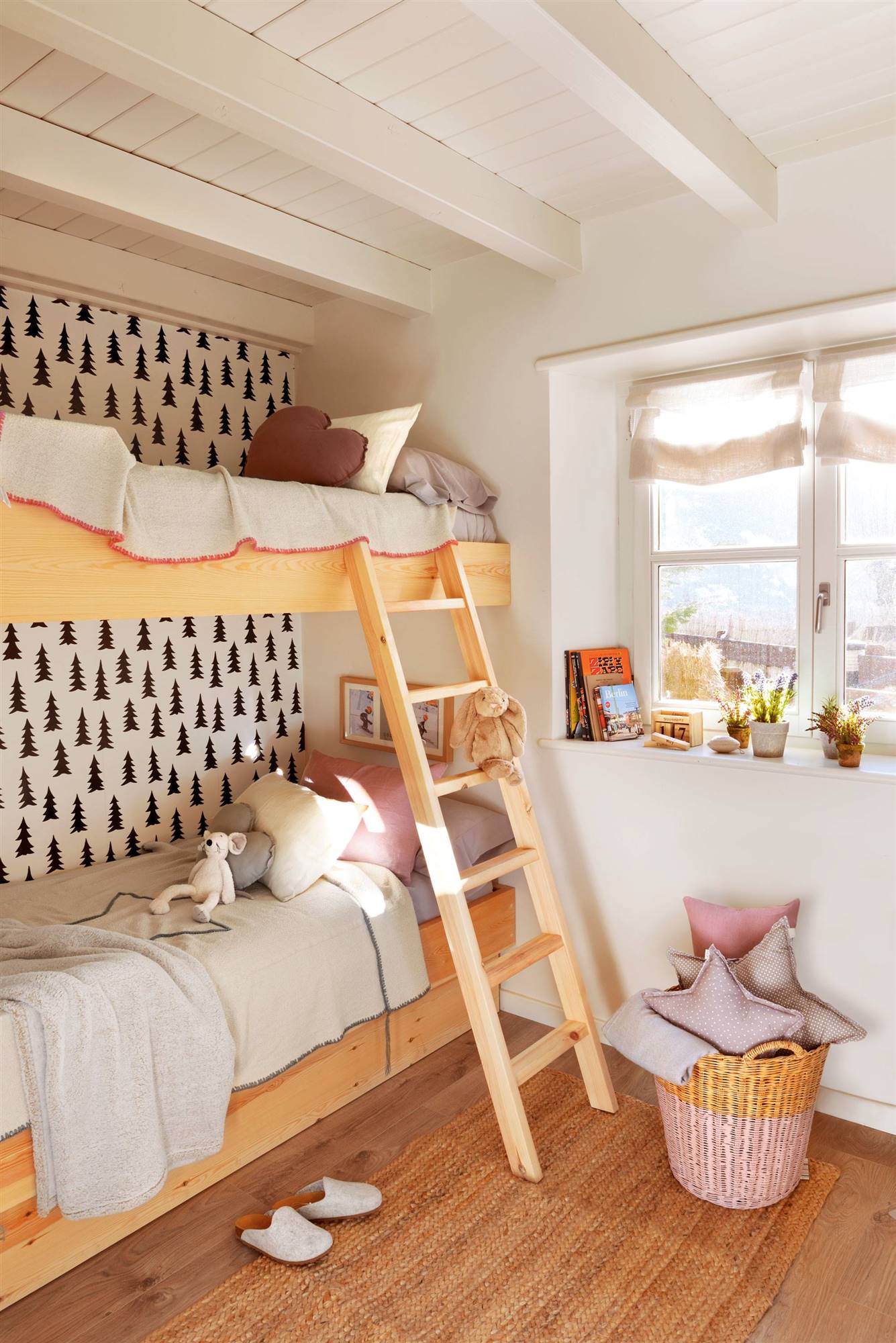 Dormitorio infantil con litera, papel pintado, cesta de mimbre y cojines.