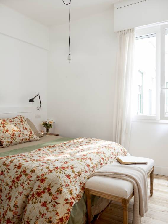 Dormitorio con paredes blancas y cortinas tipo visillo.