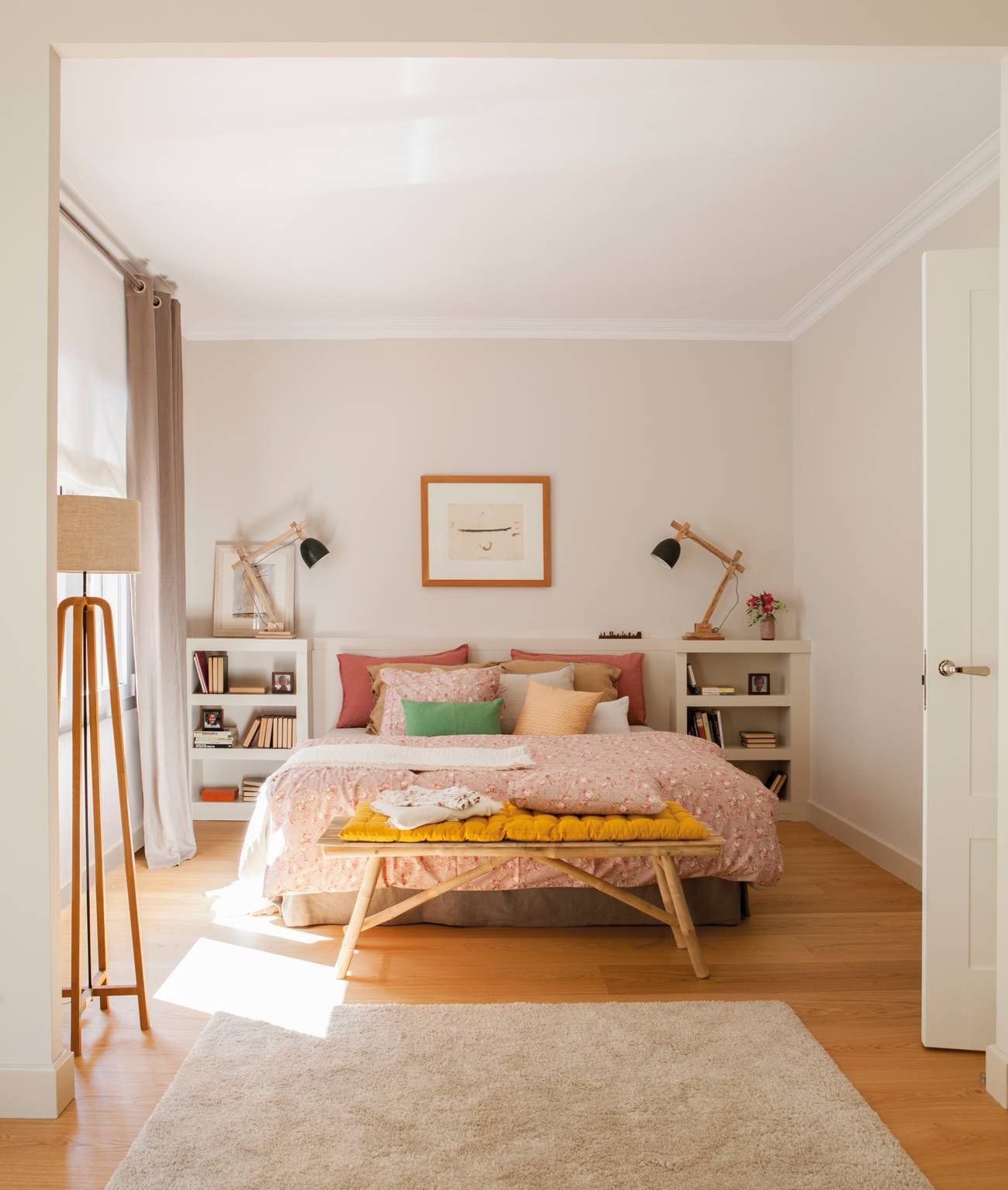Dormitorio con alfombra y lampara de pie y banqueta pies de cama y tonos en rosa.