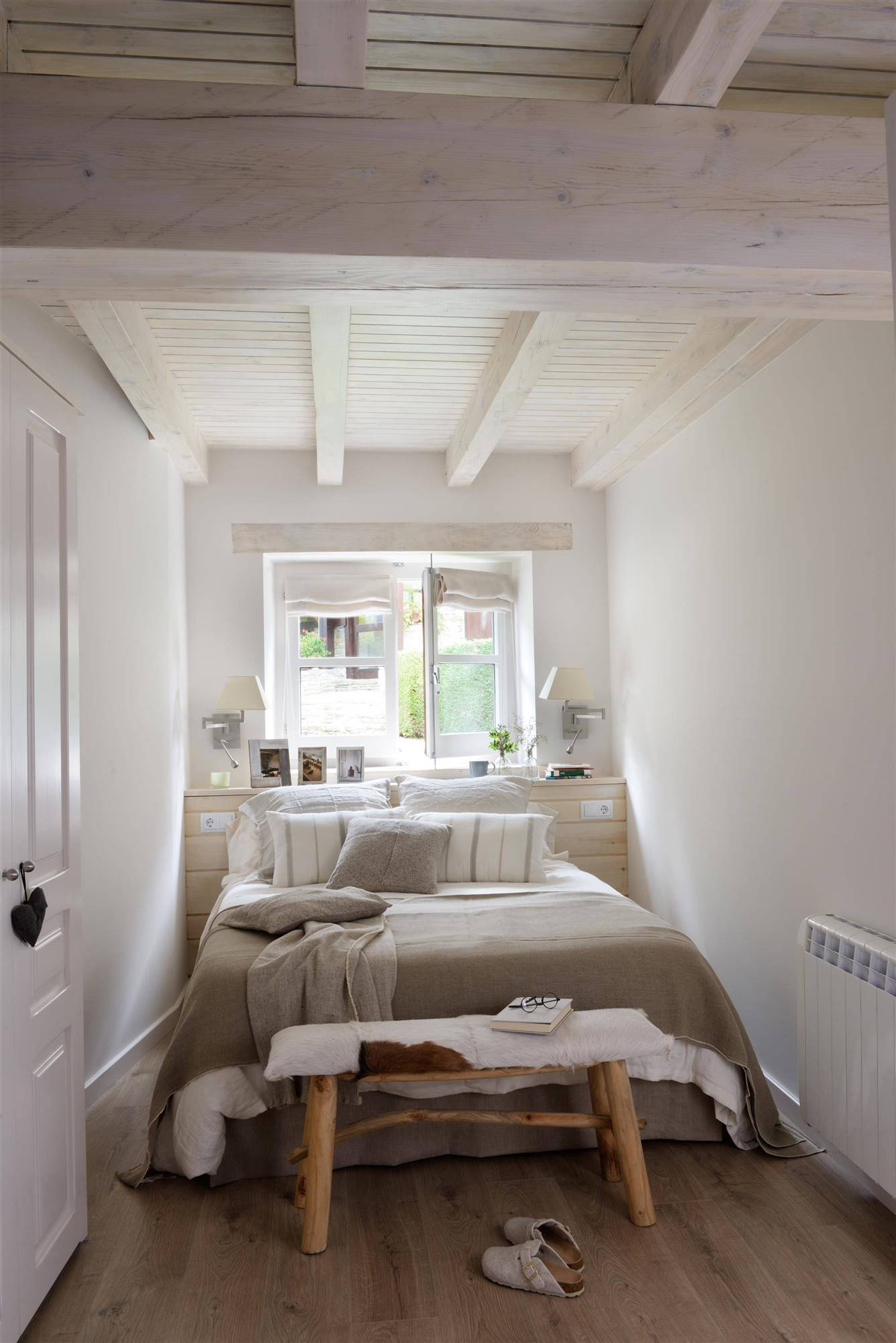 Dormitorio de estilo nórdico con cabecero realizado a medida y banco a los pies de la cama.