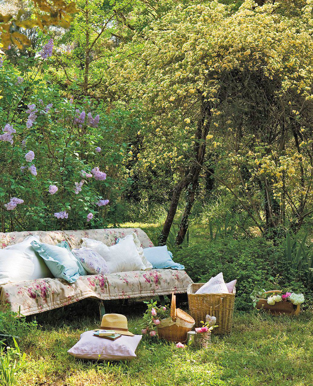 JARDIN banco cubierto con colcha y cojines en medio de un jardin de rosas 1036x1280