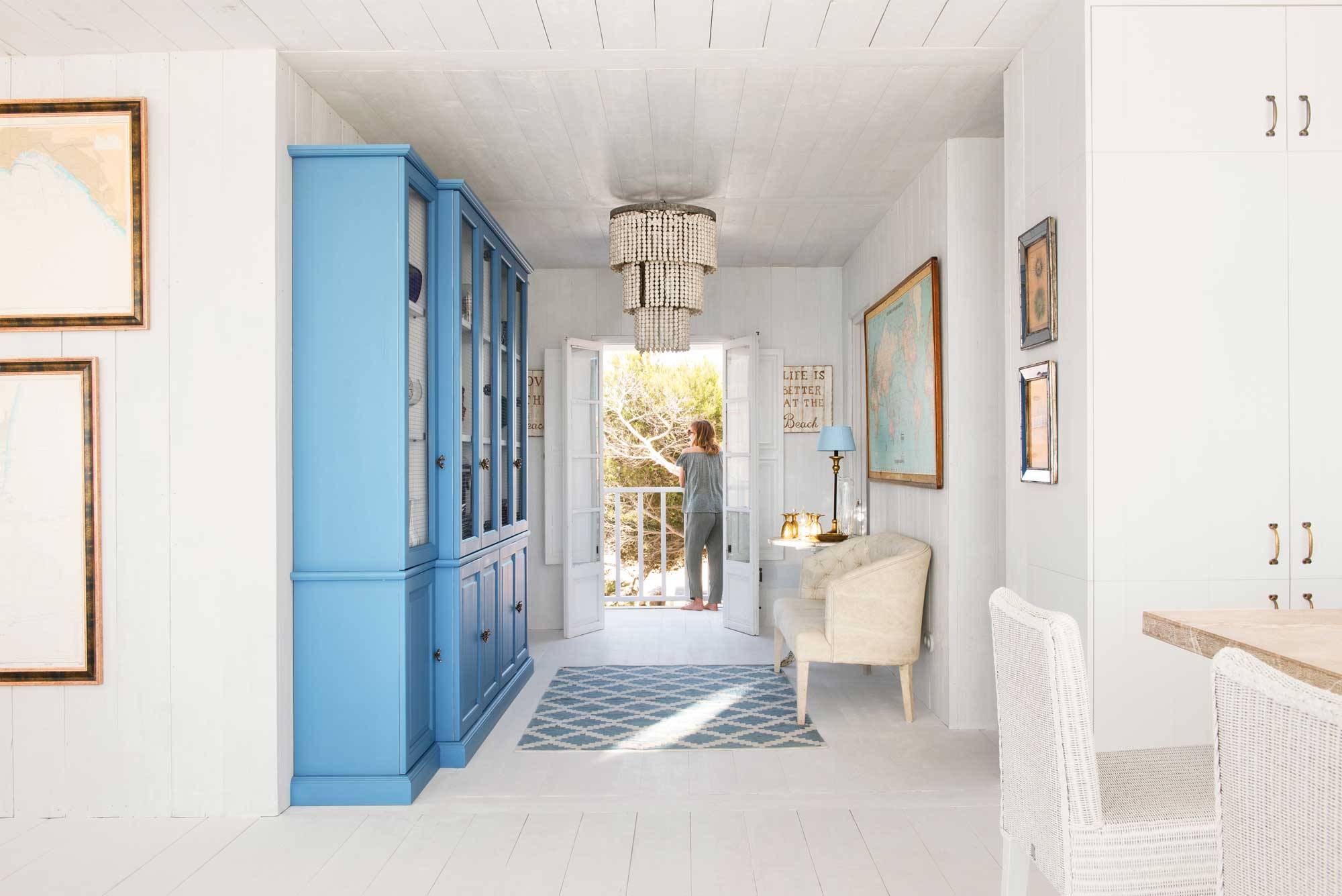 Recibidor con alacenas pintadas en color azul con paredes y suelos en color blanco.