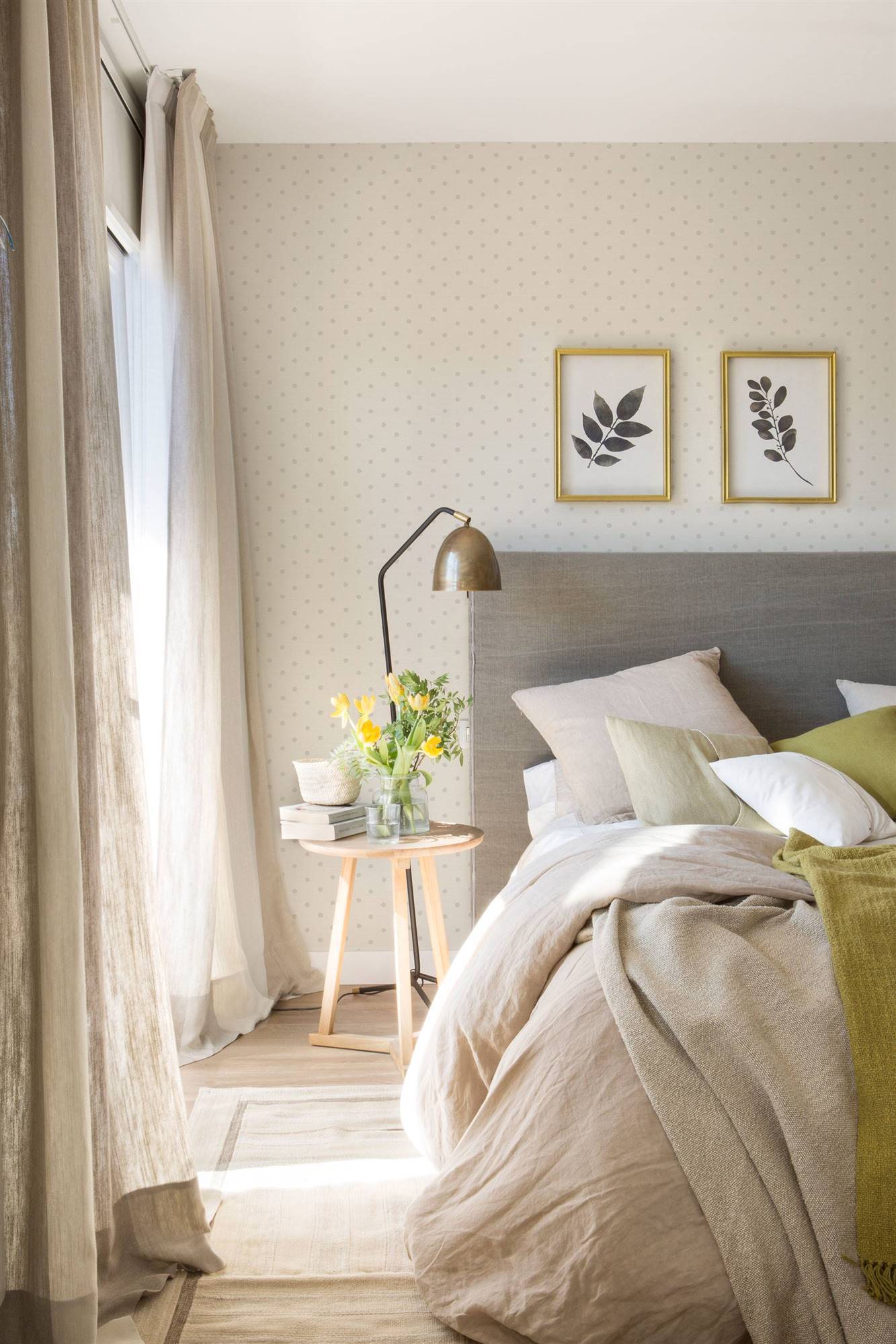Dormitorio con papel pintado de lunares y cabecero tapizado en gris. 