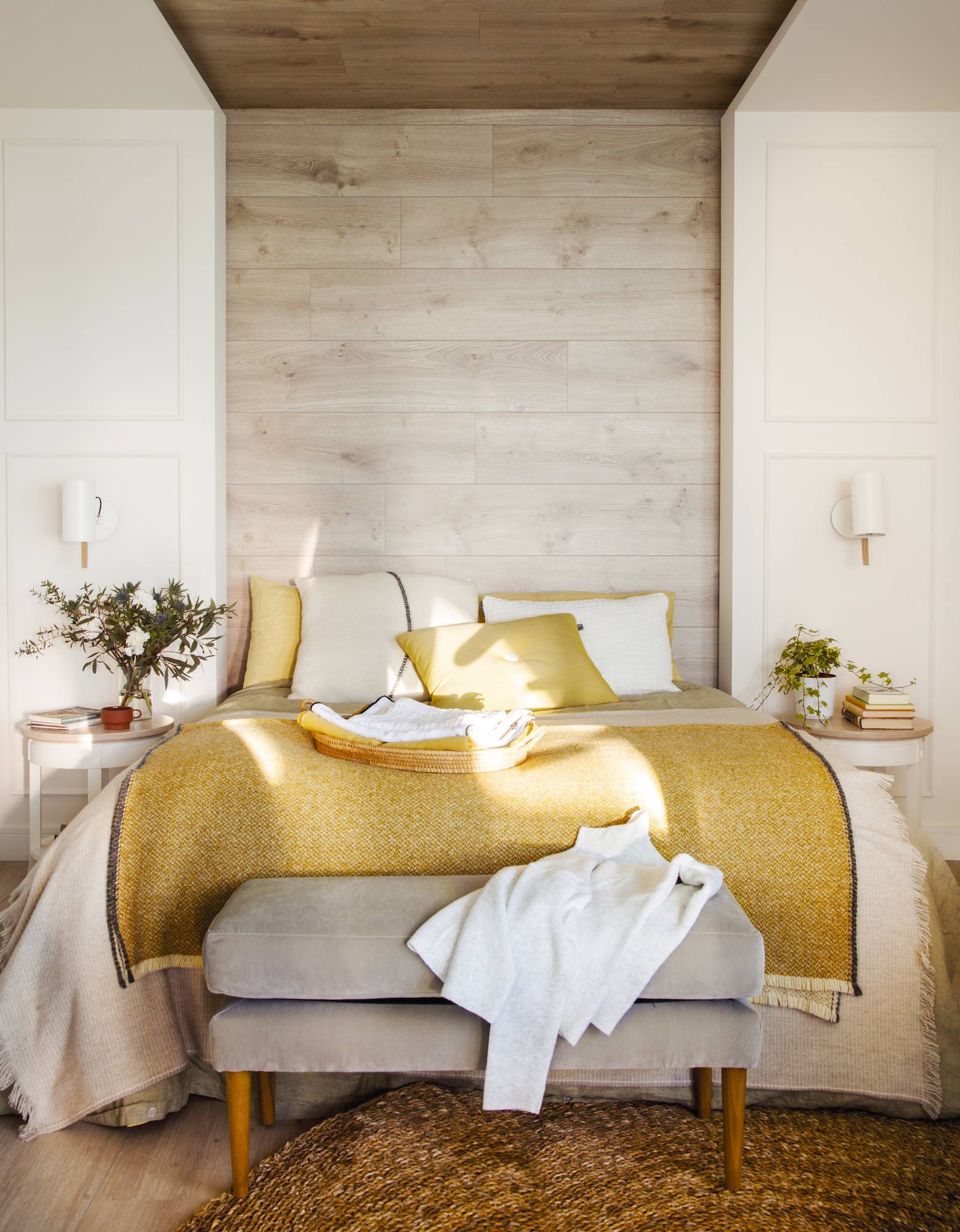Dormitorio con cabecero de madera y ropa de color ocre. 