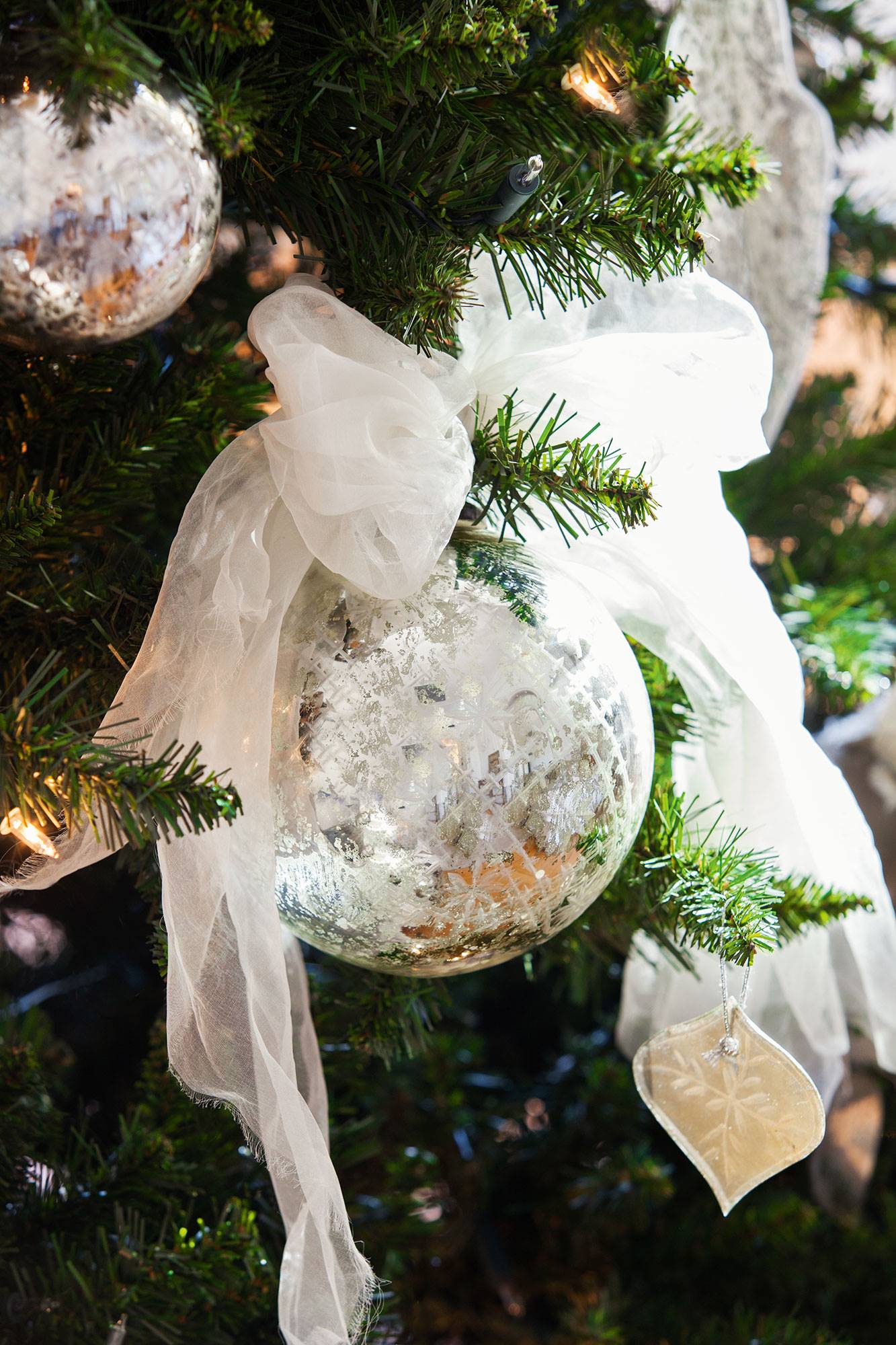 Detalle de bola de Navidad plateada con lazo blanco