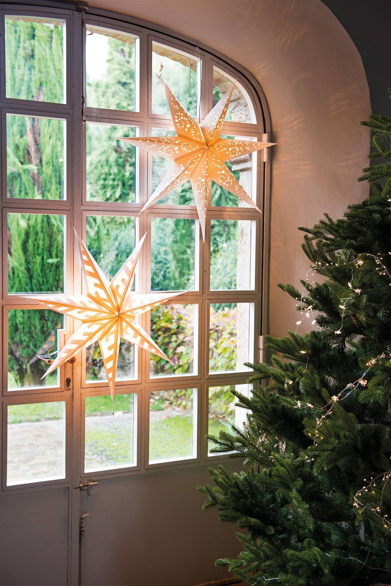 Iluminación de Navidad con estrellas de papel en la ventana.