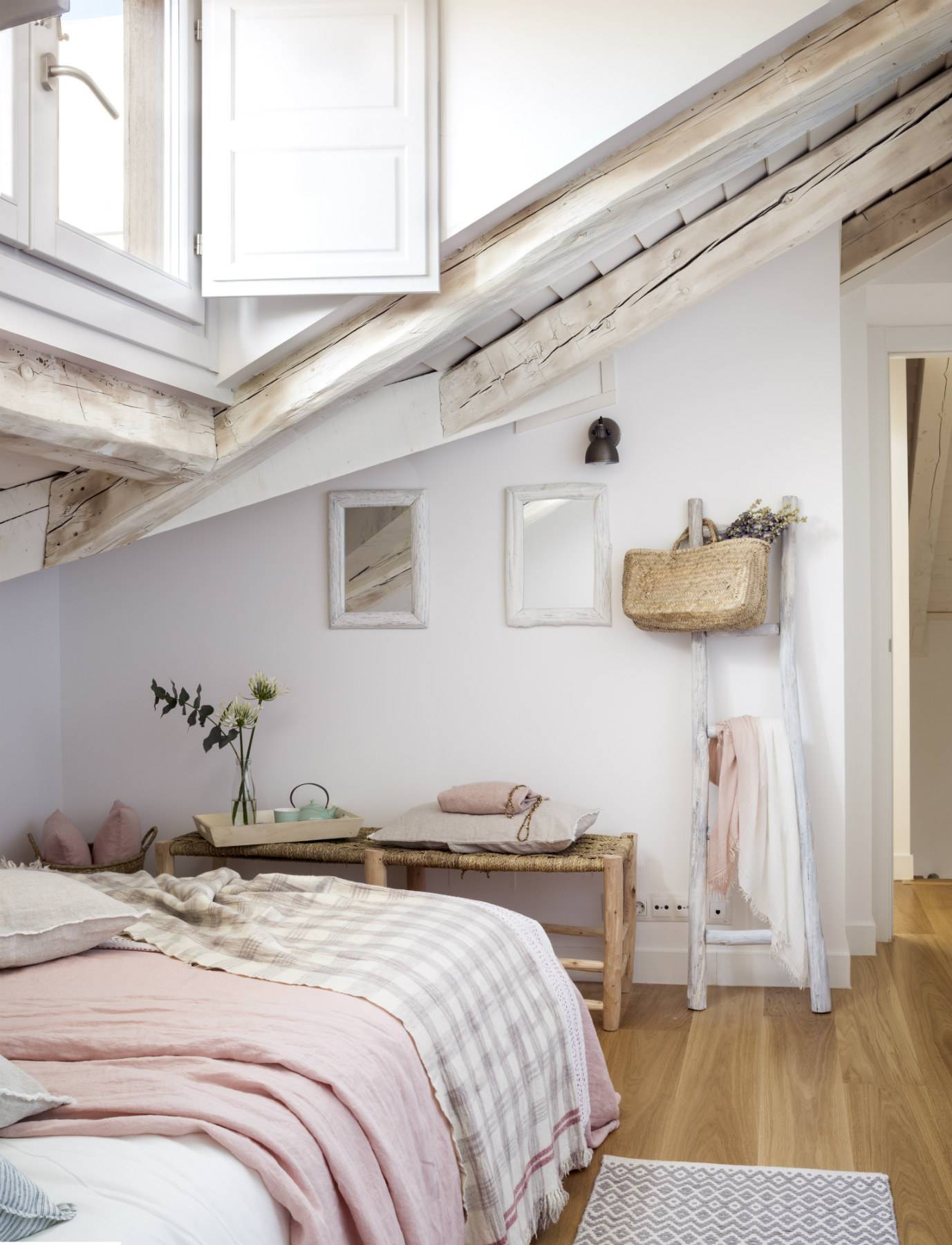 Dormitorio con techo abuhardillado con complementos de madera y mimbre. 