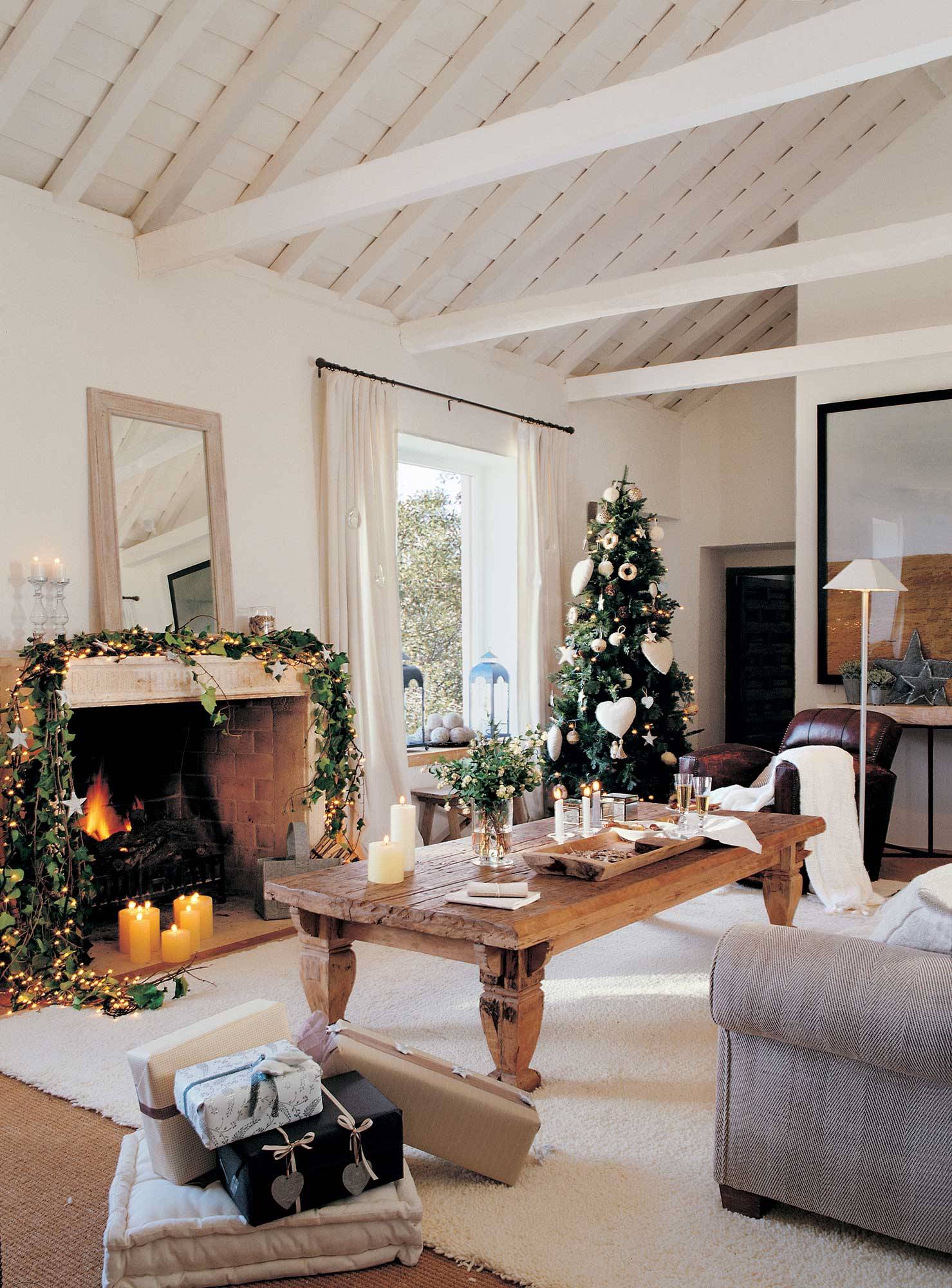 Salón con chimenea con guirnalda de hiedra, luces y estrellas. Árbol de Navidad en el fondo decorado con corazones. 