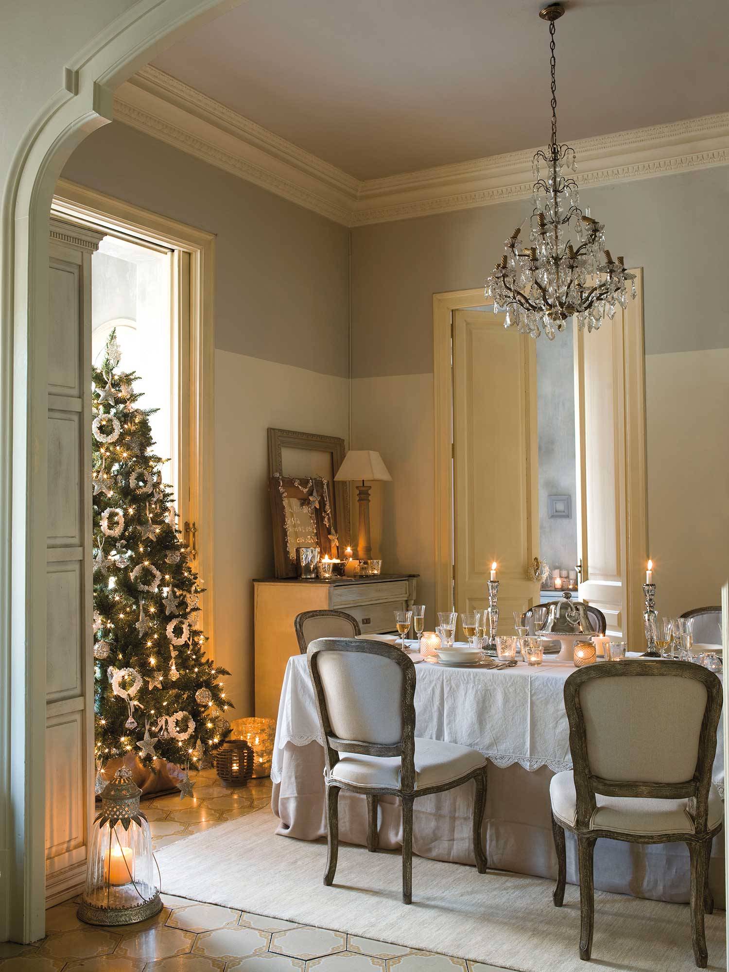 Comedor clásico con lámpara de araña y árbol de Navidad.