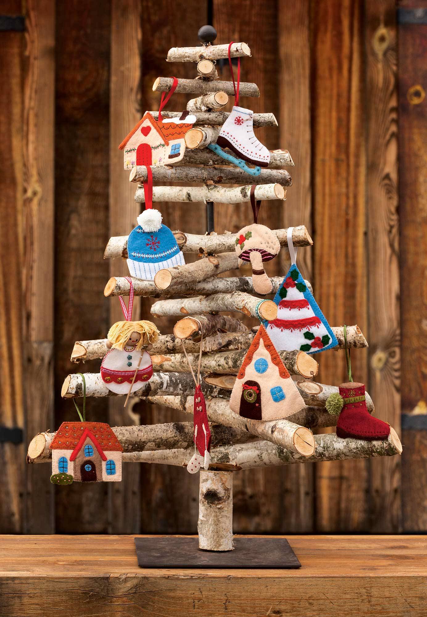 Árbol de Navidad hecho de troncos decorado con adornos de fieltro caseros con motivos bordados. 