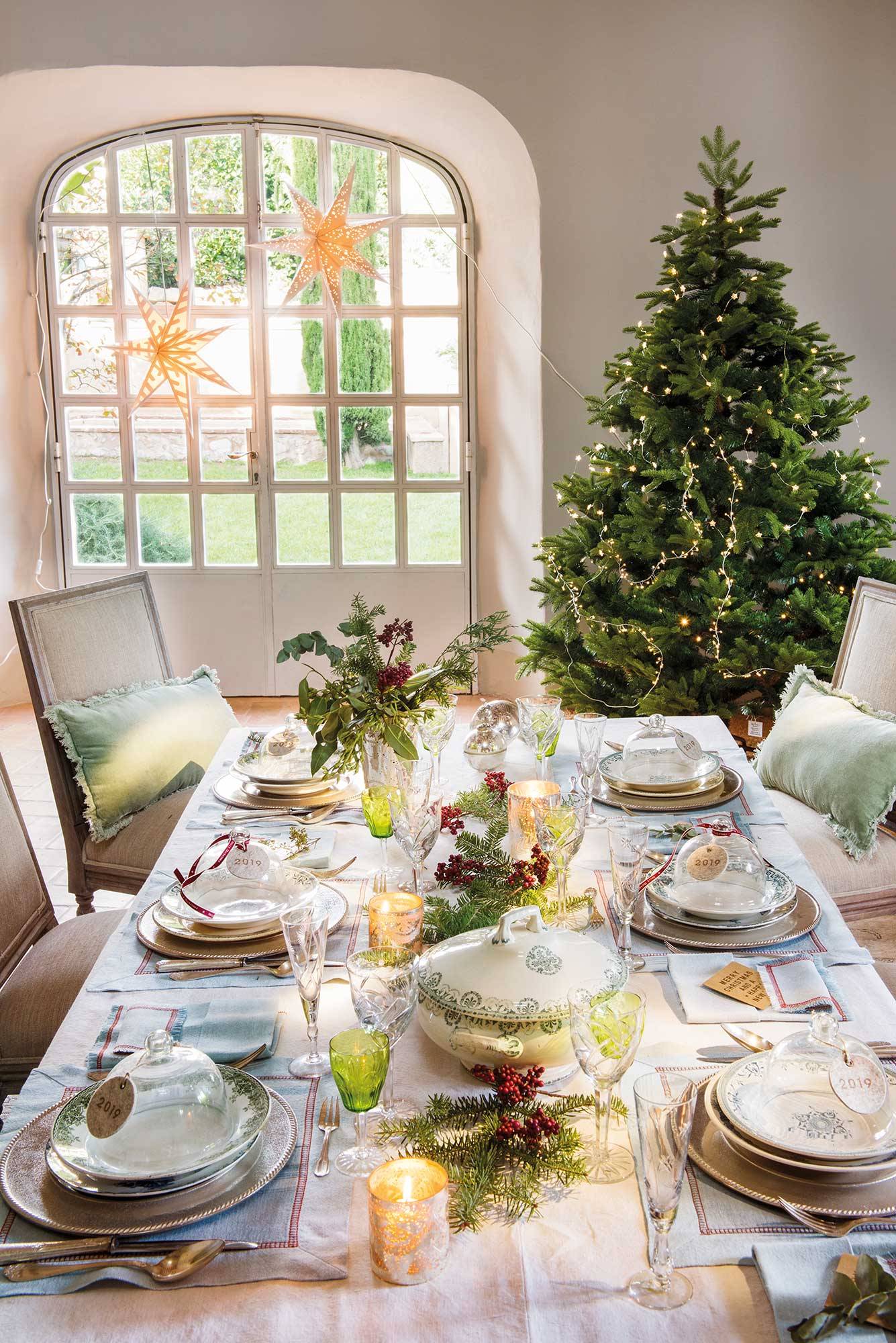 Comedor con mesa navideña y árbol de Navidad decorado con una guirnalda de luz. 