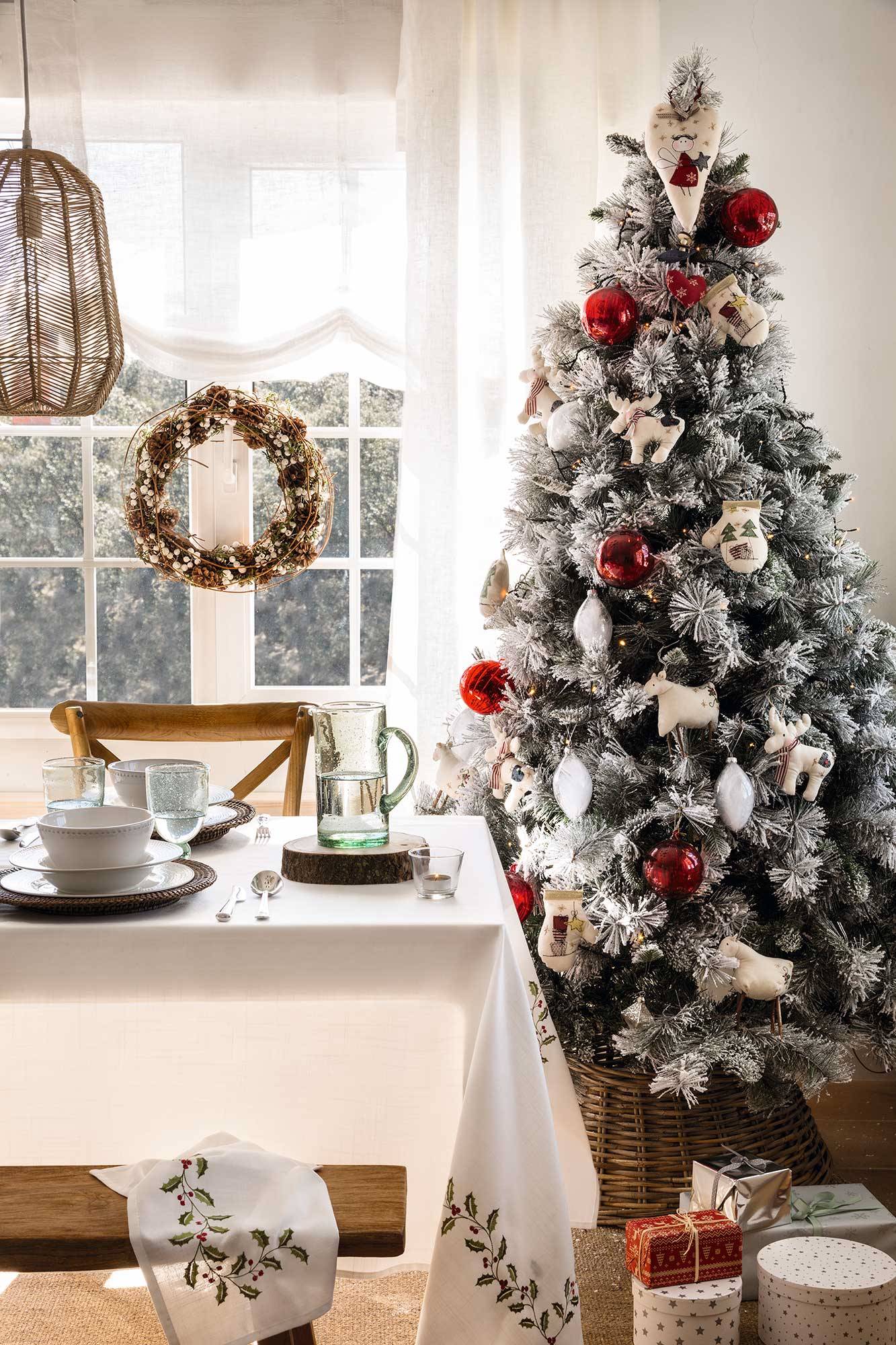 Comedor con decoración navideña y árbol de Navidad nevado con adornos clásicos. 