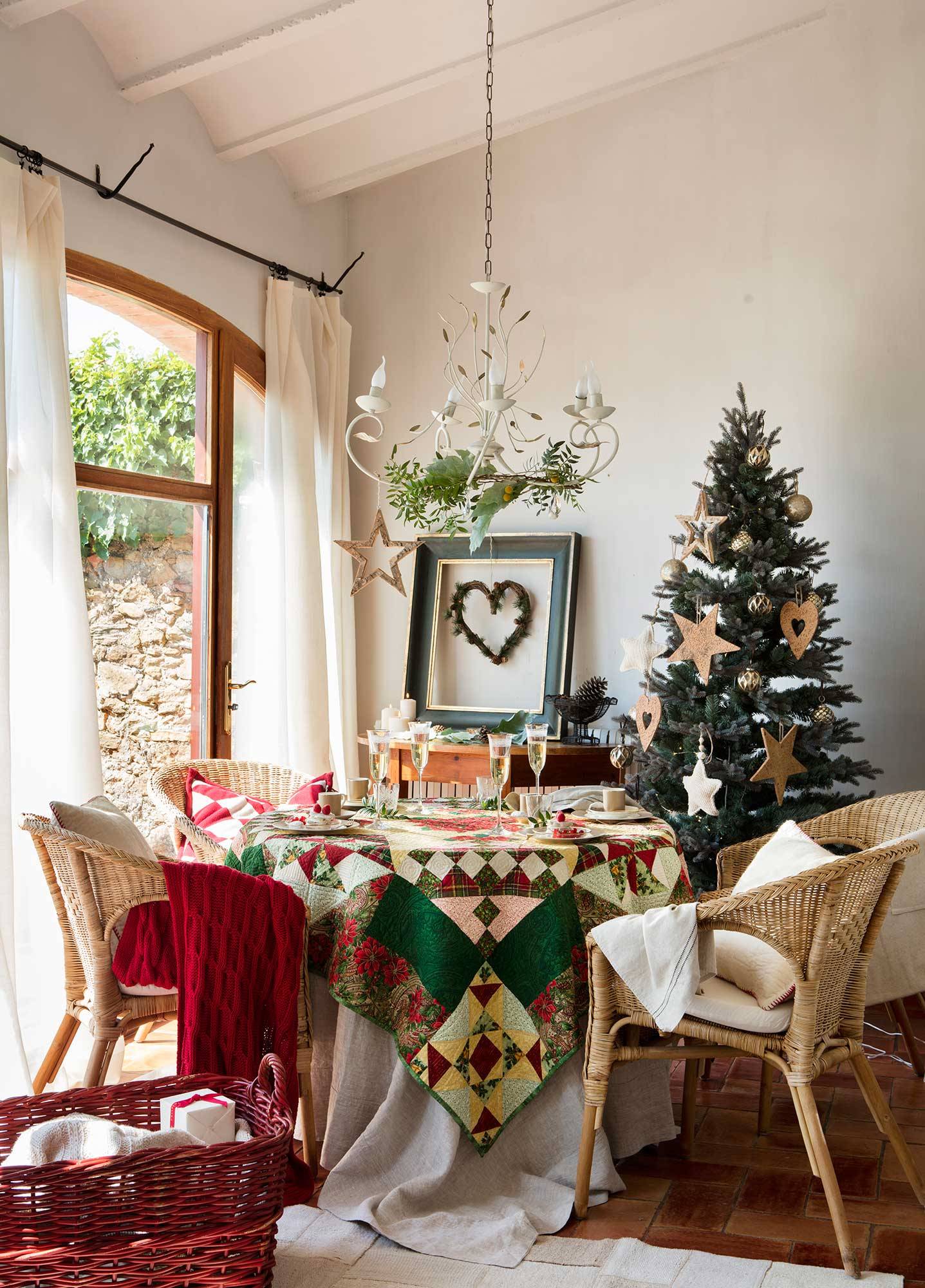 Comedor navideño con mantel de patchwork y árbol de Navidad con grandes adornos en forma de estrella y corazón dorados. 
