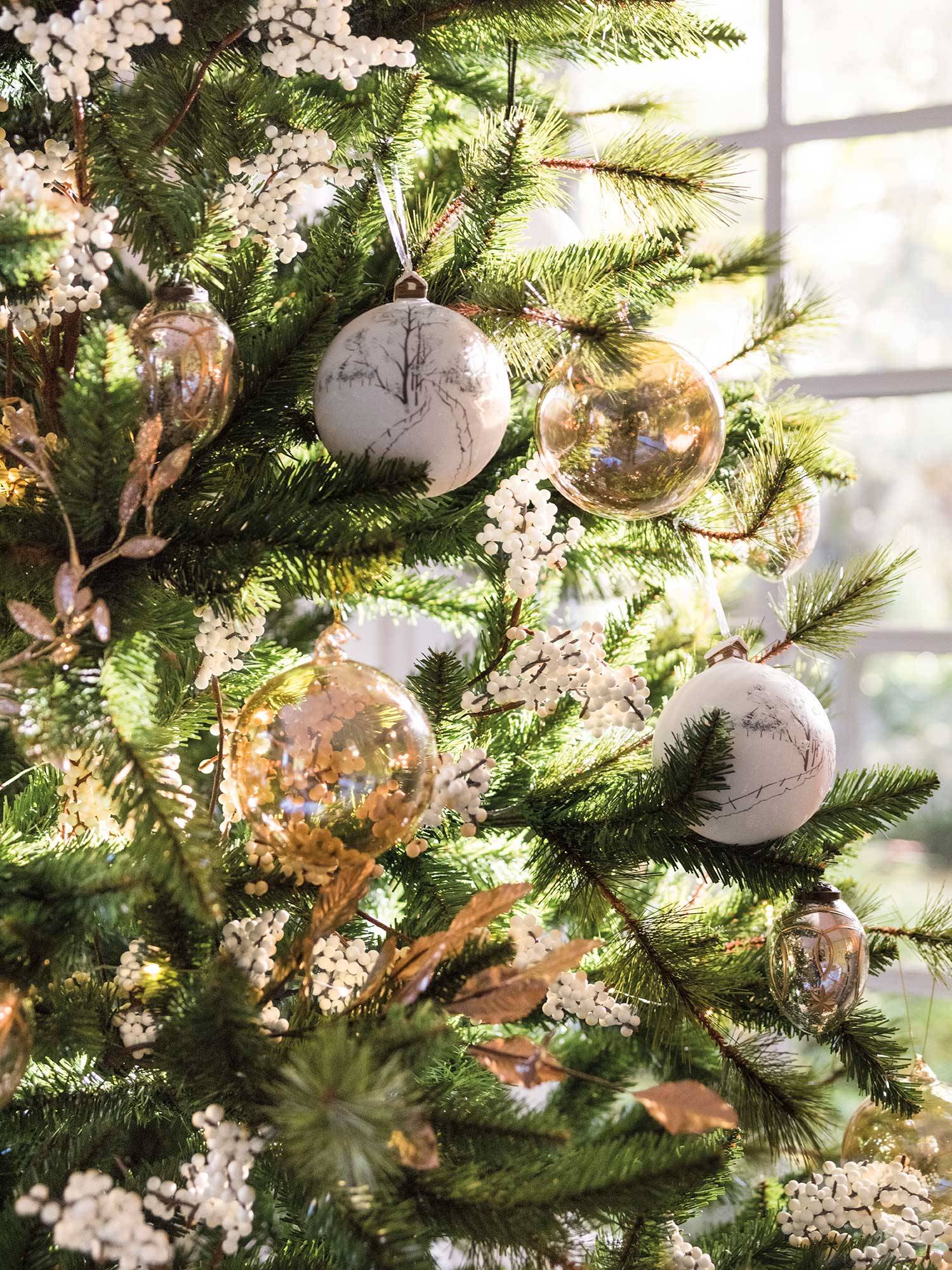 Árbol de Navidad con adornos blancos, de cristal y dorados.