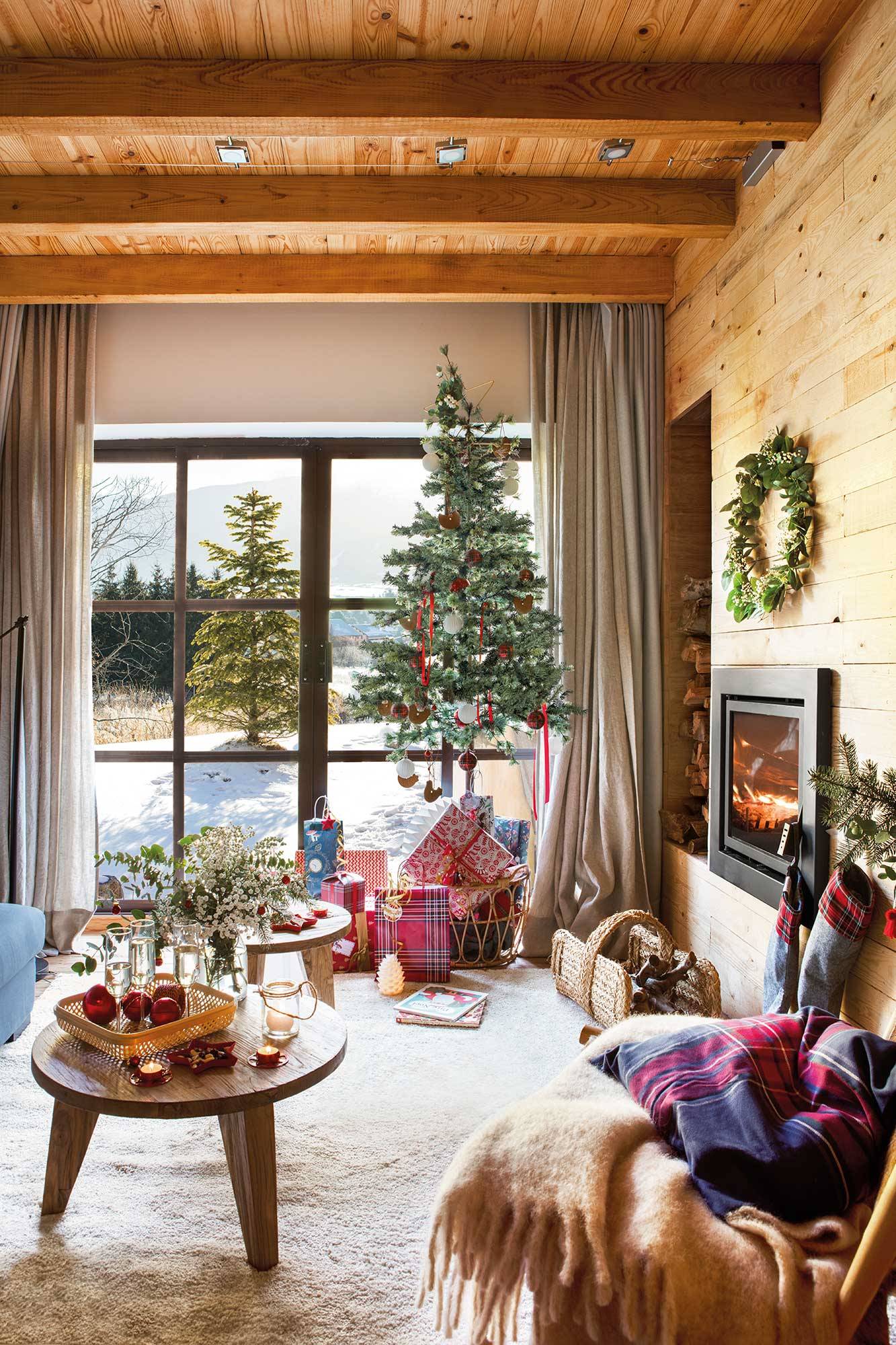 Salón rústico con paredes de madera, chimenea, alfombra blanca y arbolito de Navidad. 