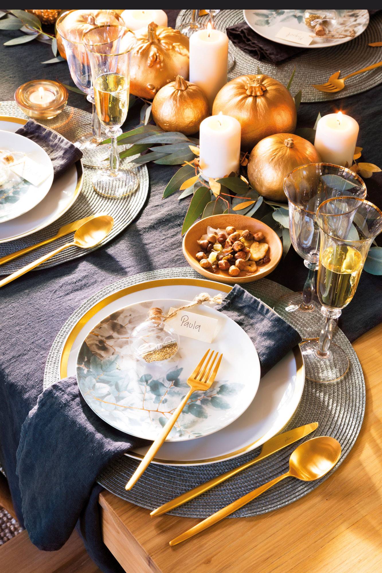 Mesa vestida por Navidad con platos con dibujos y cubertería dorada. 