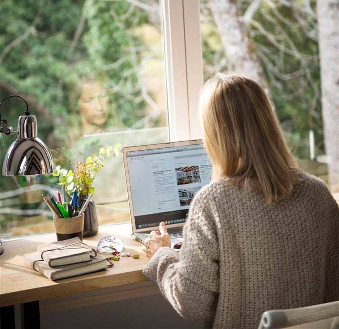 Mujer en escritorio de zona de trabajo y estudio con ordenador portátil y junto a la ventana