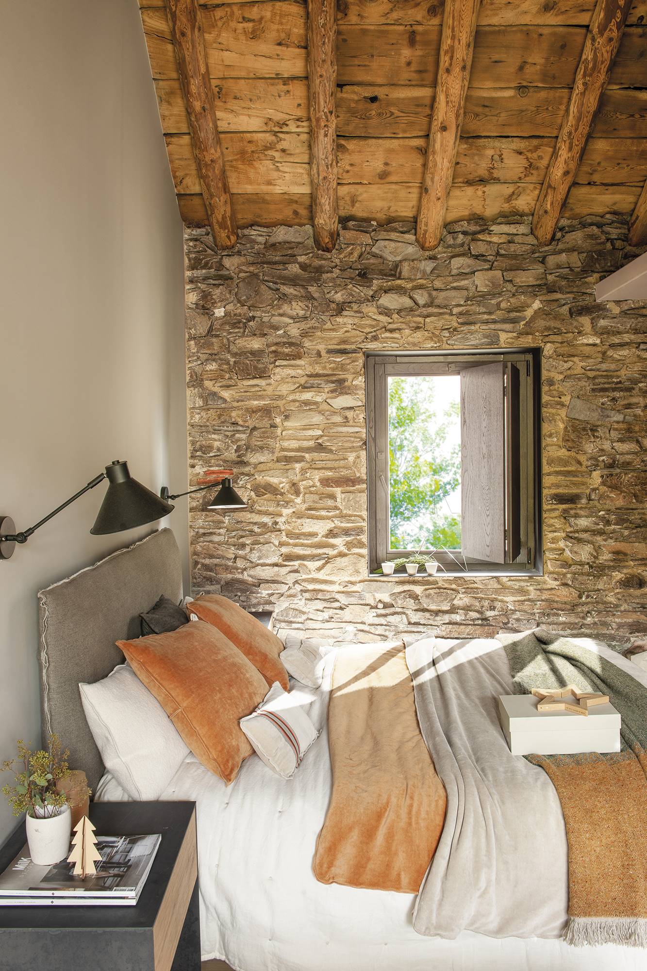 Dormitorio de casa de montaña con pared de piedra y techo de vigas