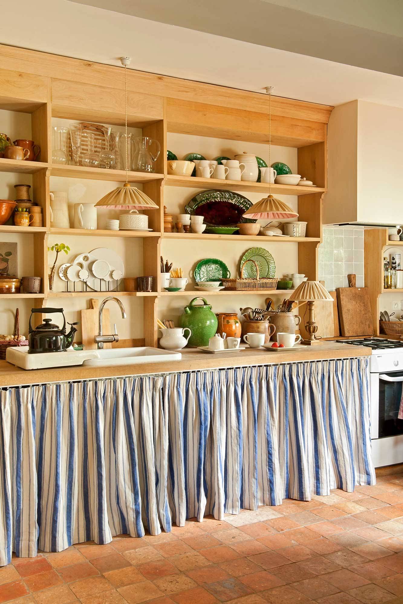 Cocina con muebles con cortinas y estantería de madera.