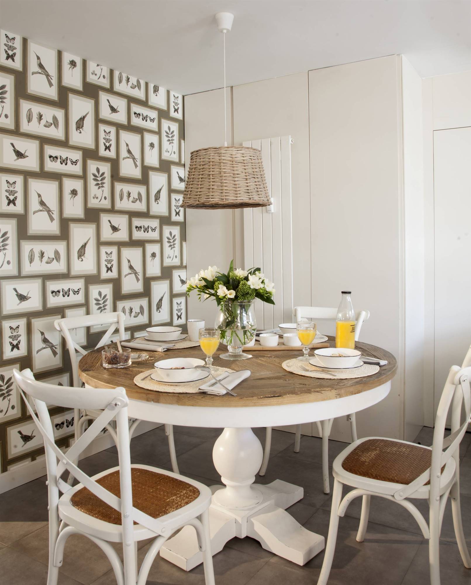 Comedor pequeño con mesa redonda y pared con papel pintado.