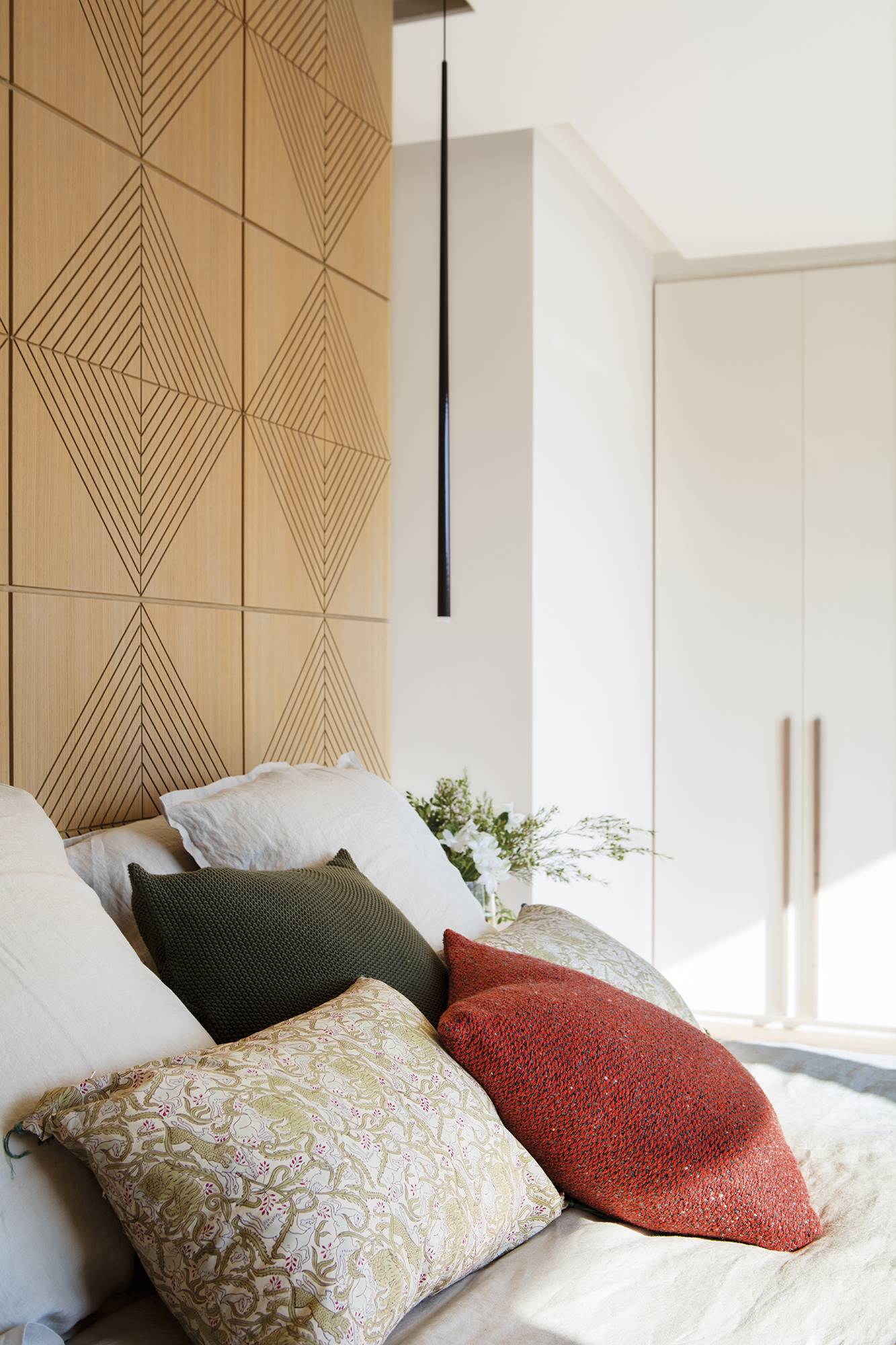 Dormitorio con cabecero con paneles cuadrados de roble fresados con diseño de rombos.