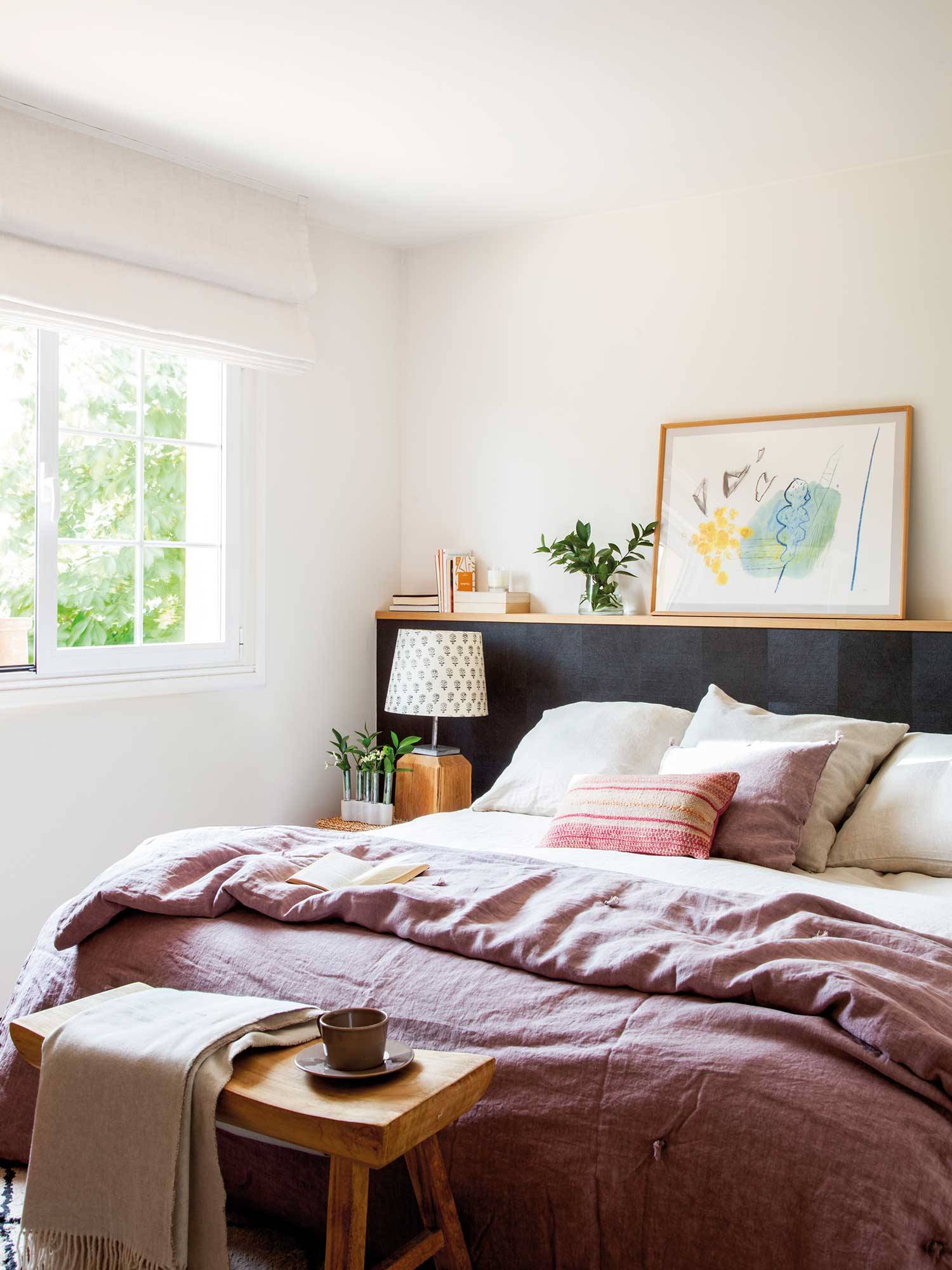 Dormitorio con cabecero de obra revestido en piel de potro gris oscuro y repisa de madera.