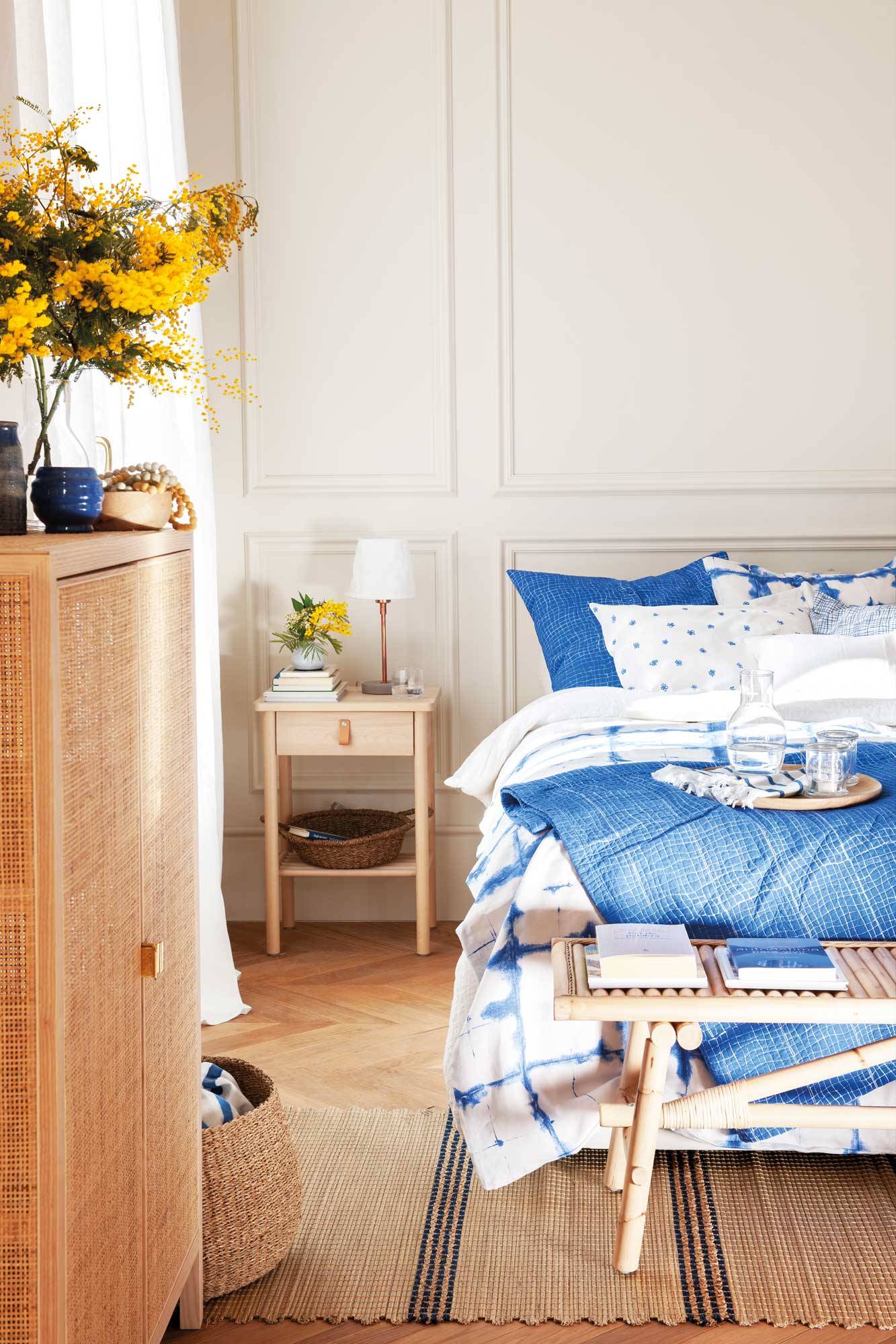 Dormitorio con pared con molduras y ropa de cama azul y blanca.