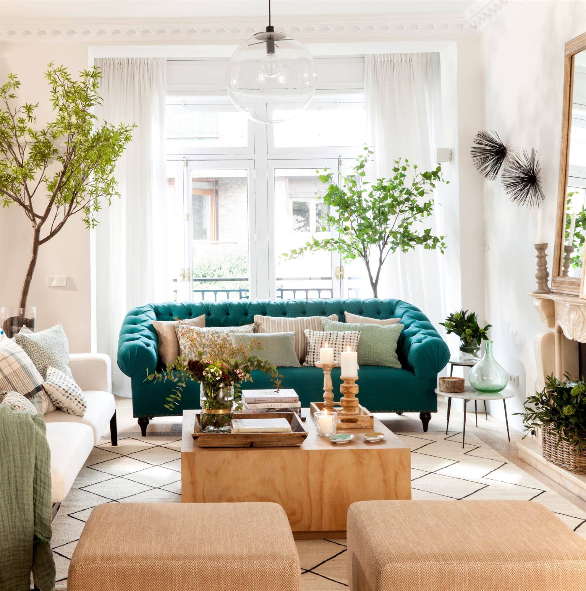 Salón con sofá chester tapizado en turquesa y muchas plantas. 