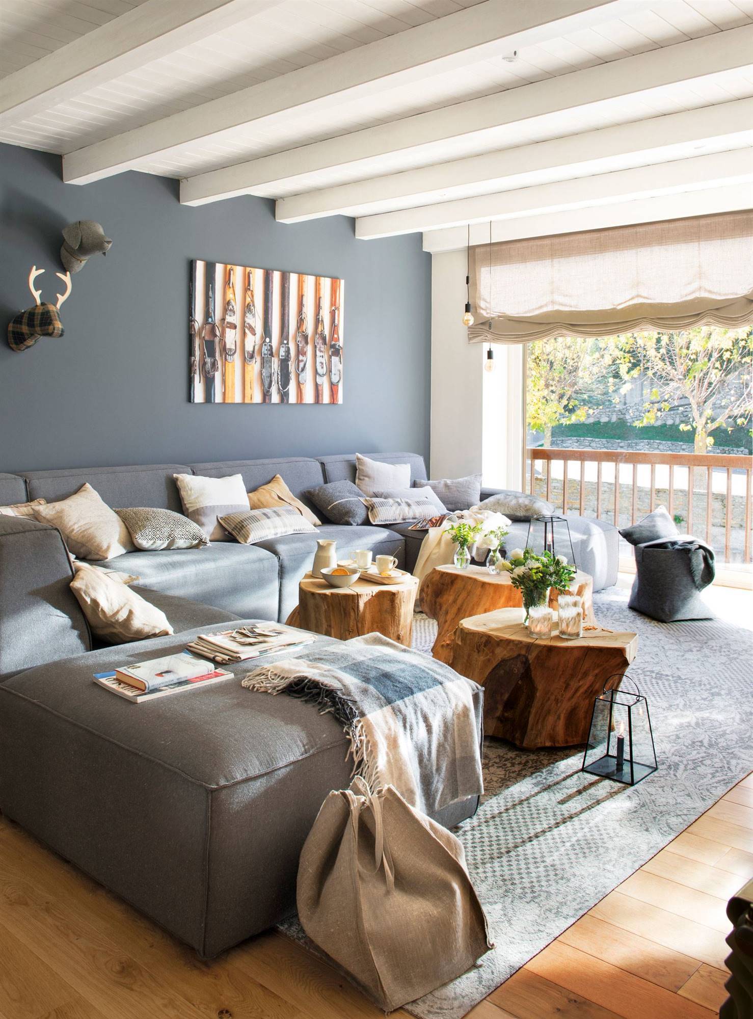 Salón de casa de montaña con pared de color gris a juego con el gran sofá modular.