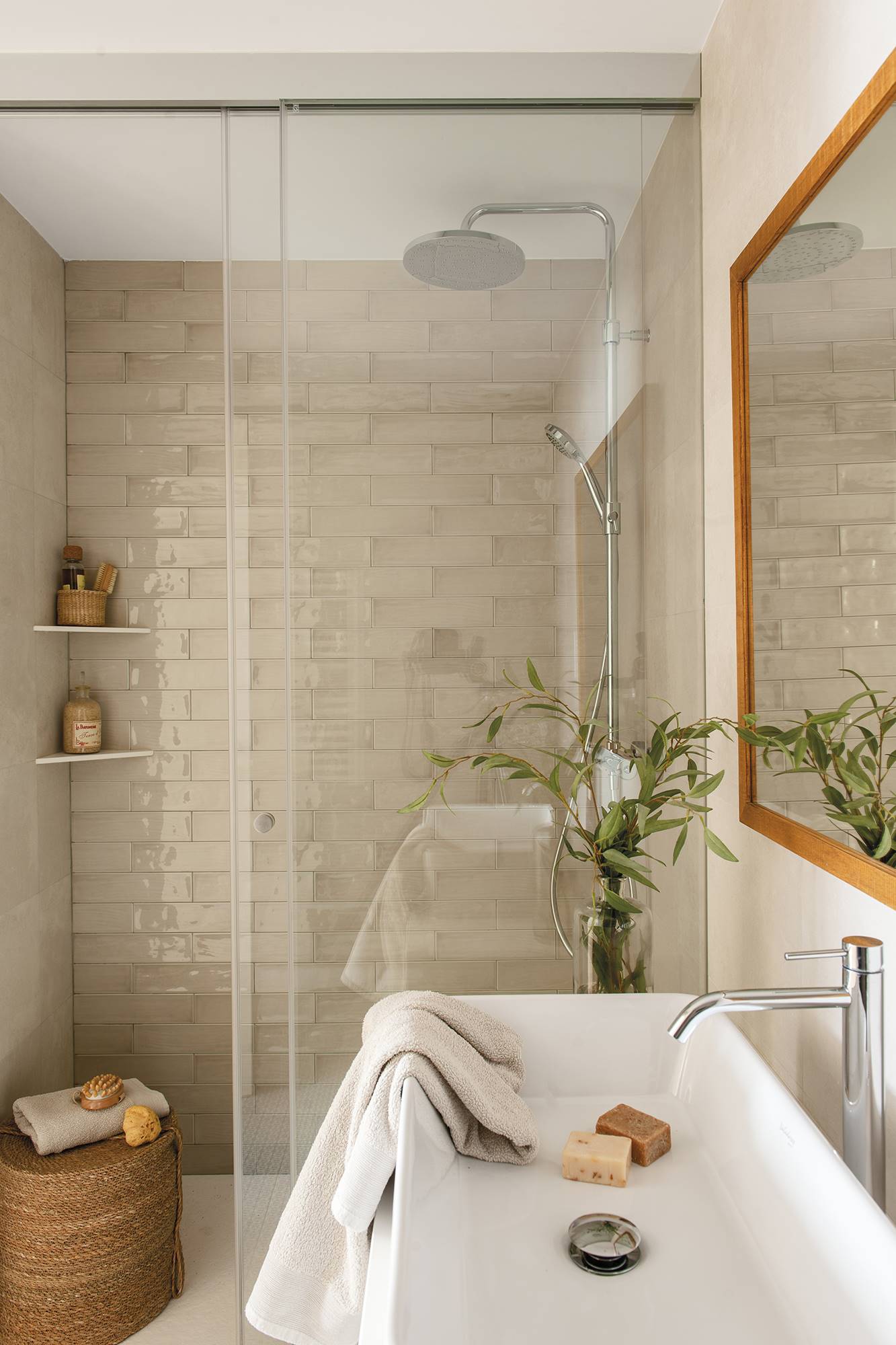 Baño con ducha con pared de baldosas esmaltadas tipo metro.