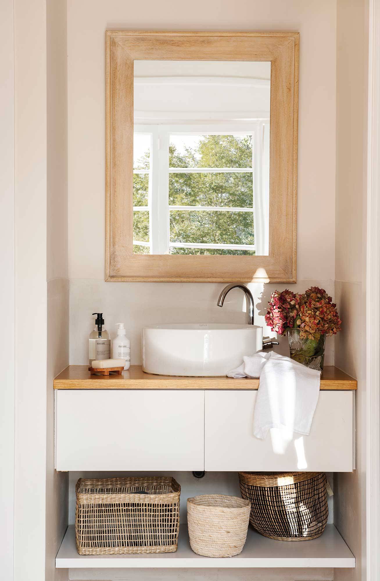 Baño pequeño con mueble volado y espejo con marco de madera.