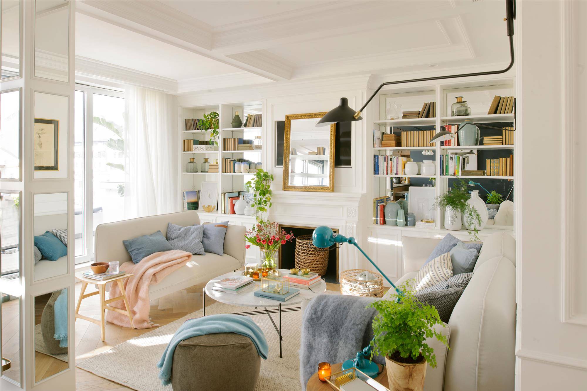 Salón pequeño blanco con dos sofás y librería.
