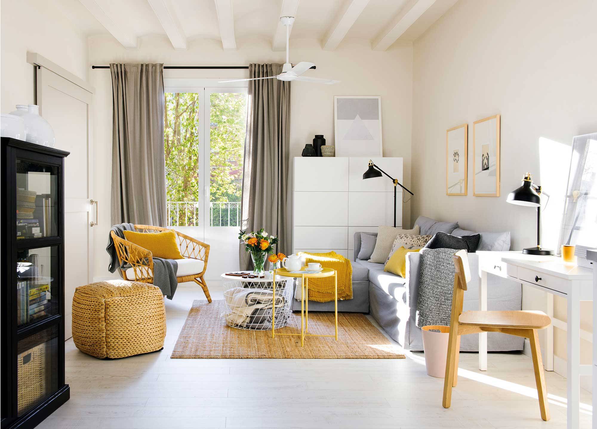 Salón pequeño en blanco con sofá gris, butaca y mesa de centro amarilla u alfombra y puff de fibras.