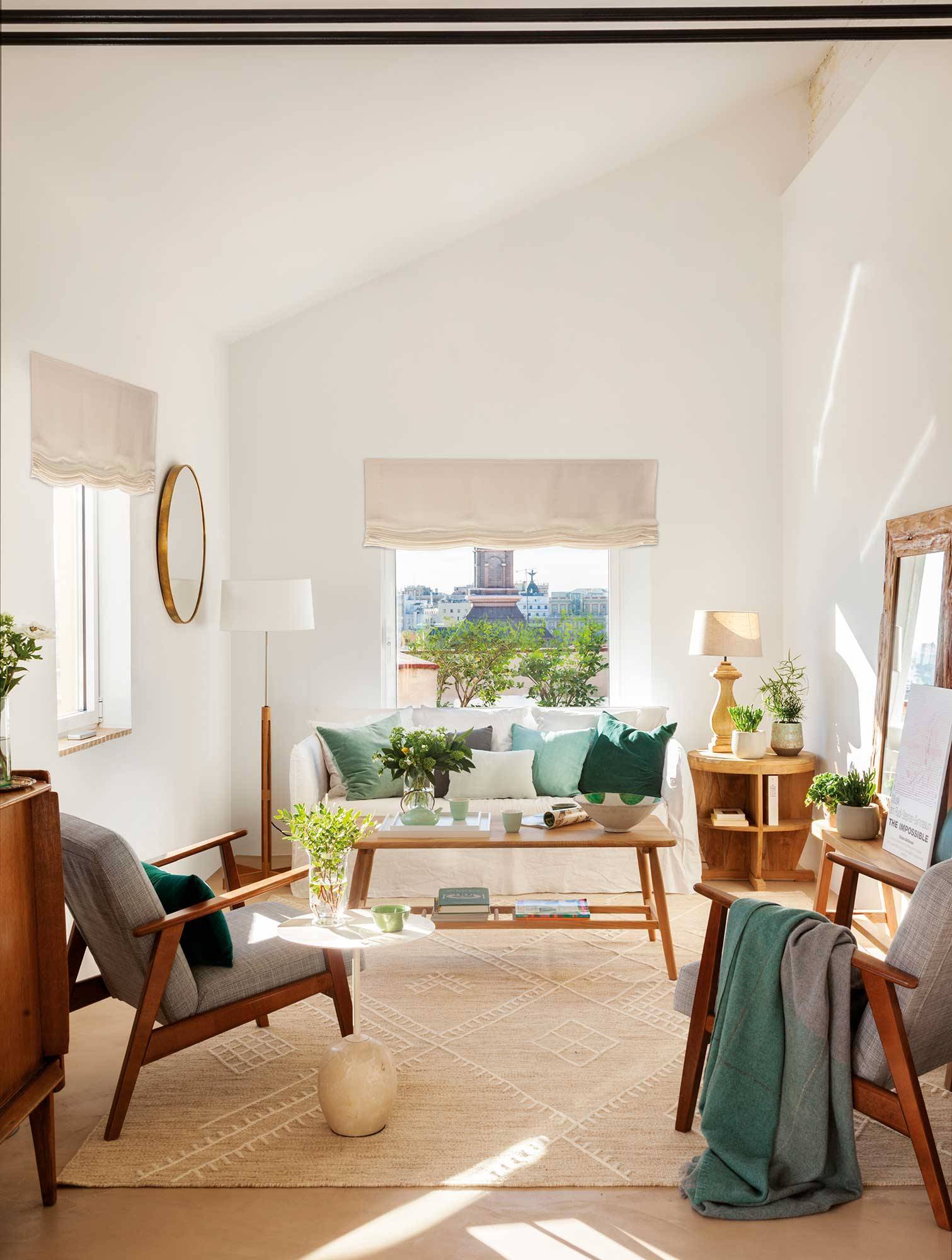 Salón pequeño en blanco con sofá blanco, butacas grises y mesa de centro de madera. 