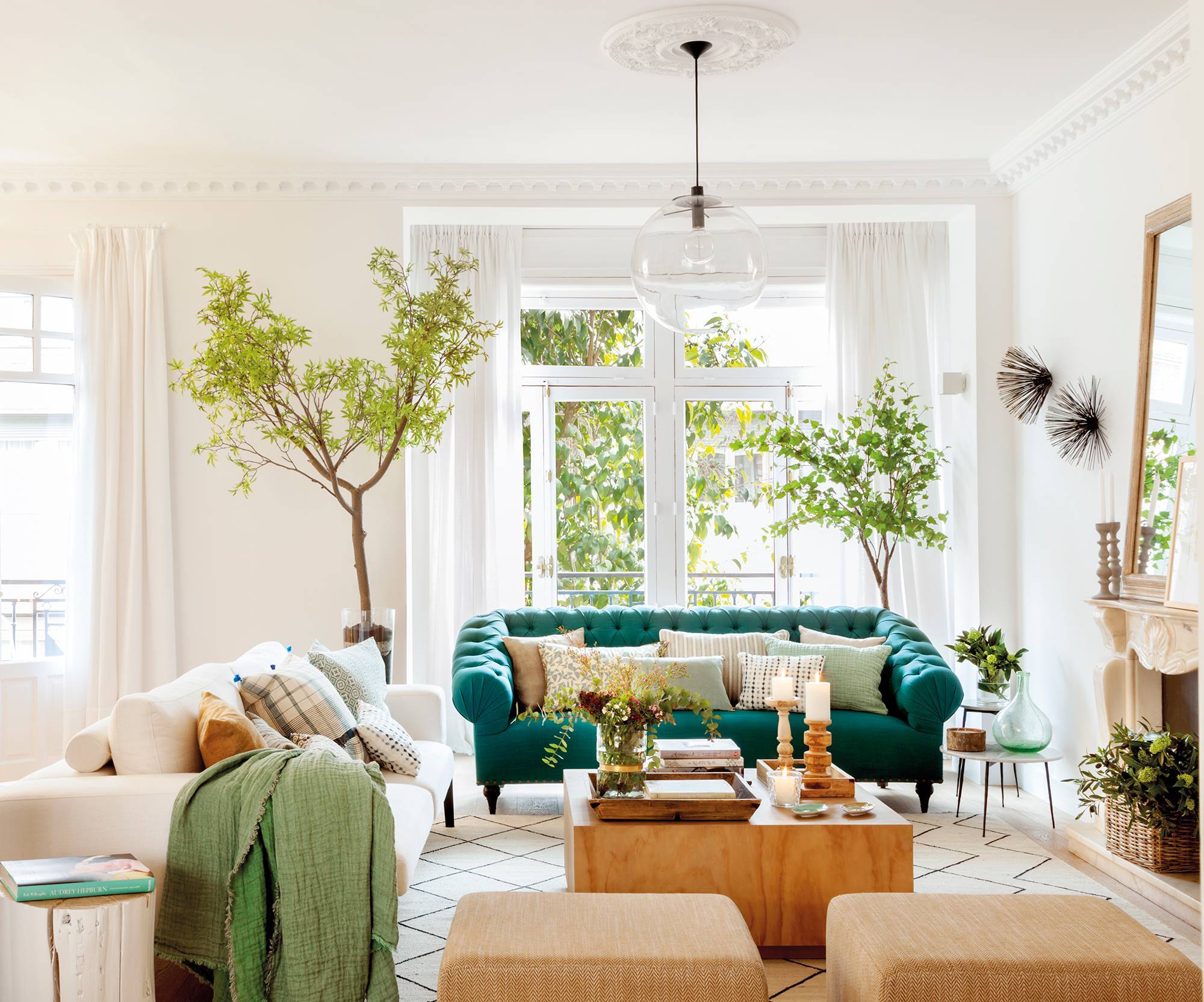 Salón elegante con sofá chester verde y paredes con molduras blancas. 
