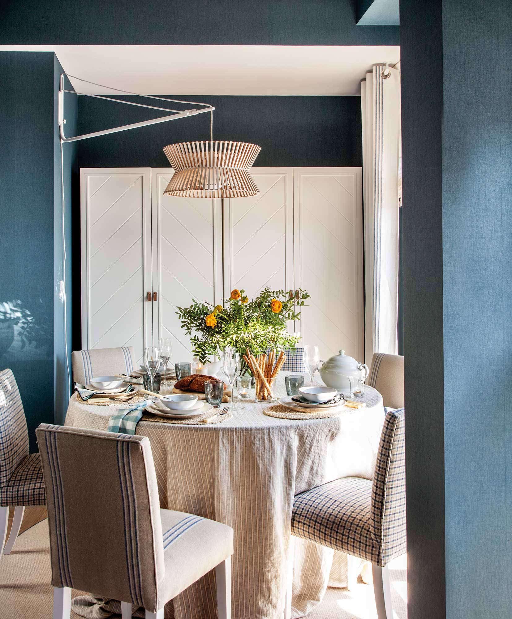 Comedor pequeño con mesa redonda y papel azul en las paredes. 