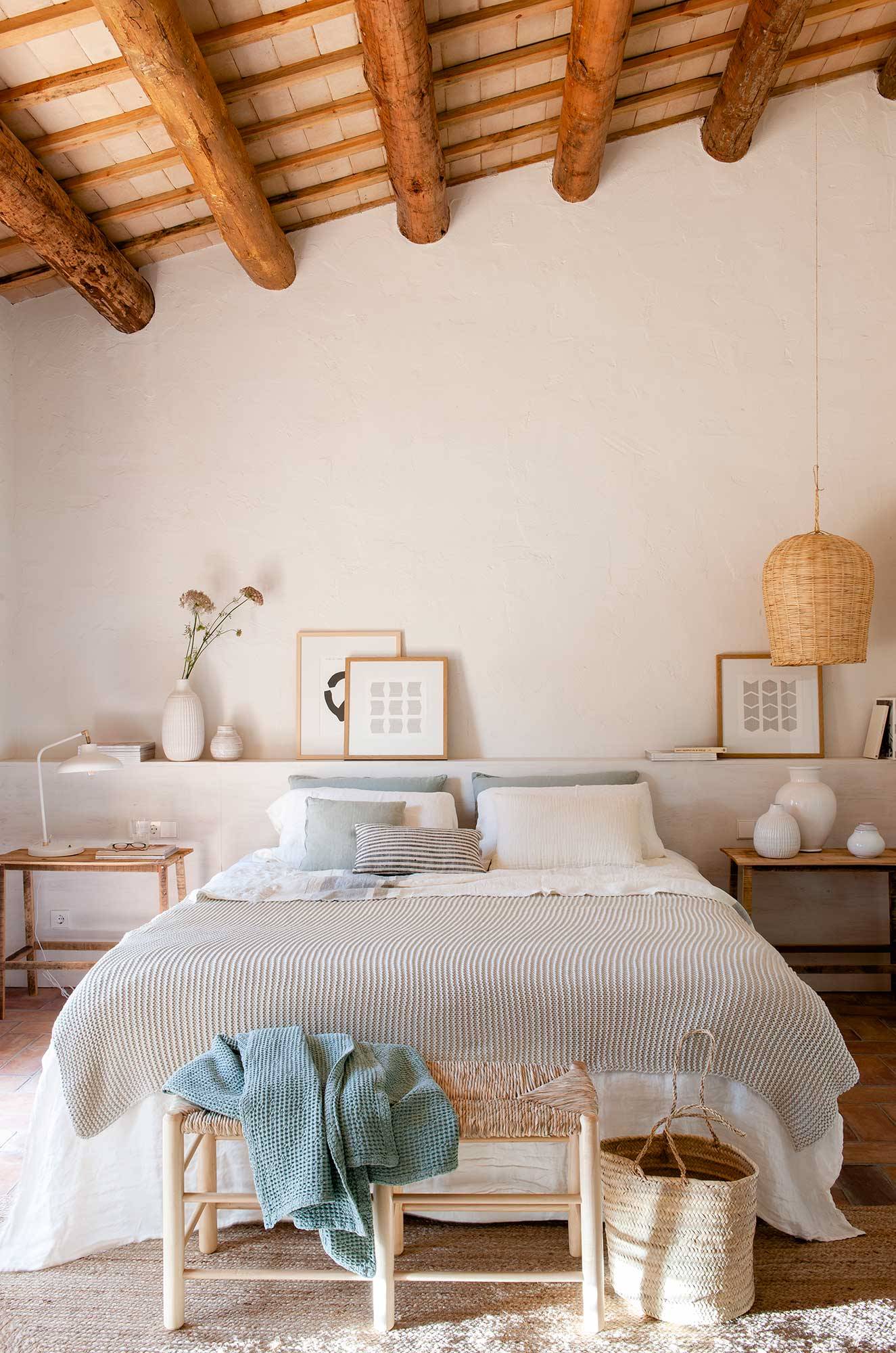 Dormitorio de primavera abuhardillado con vigas de madera y ropa de cama en blanco, gris y azul.