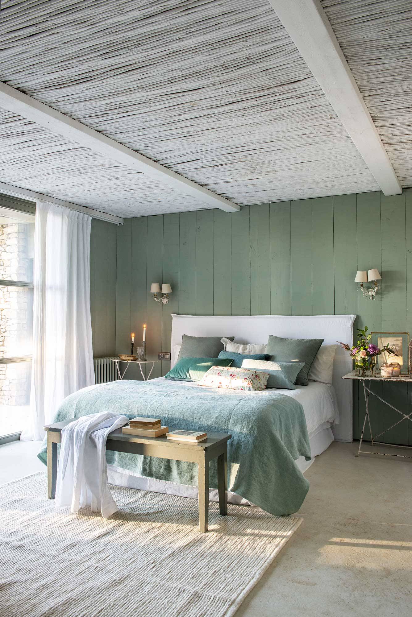 Dormitorio de primavera de estilo vintage con vigas de madera y pared de lamas pintadas en verde.